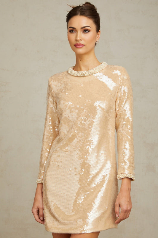 Woman wearing short beige dress with faux pearl and sequin embellishments