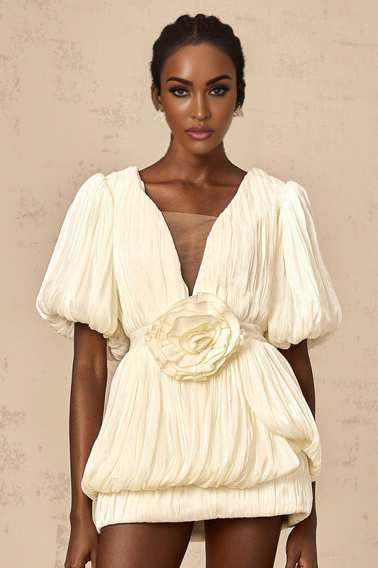 Woman wearing short pleated dress in neutral tones with floral appliques