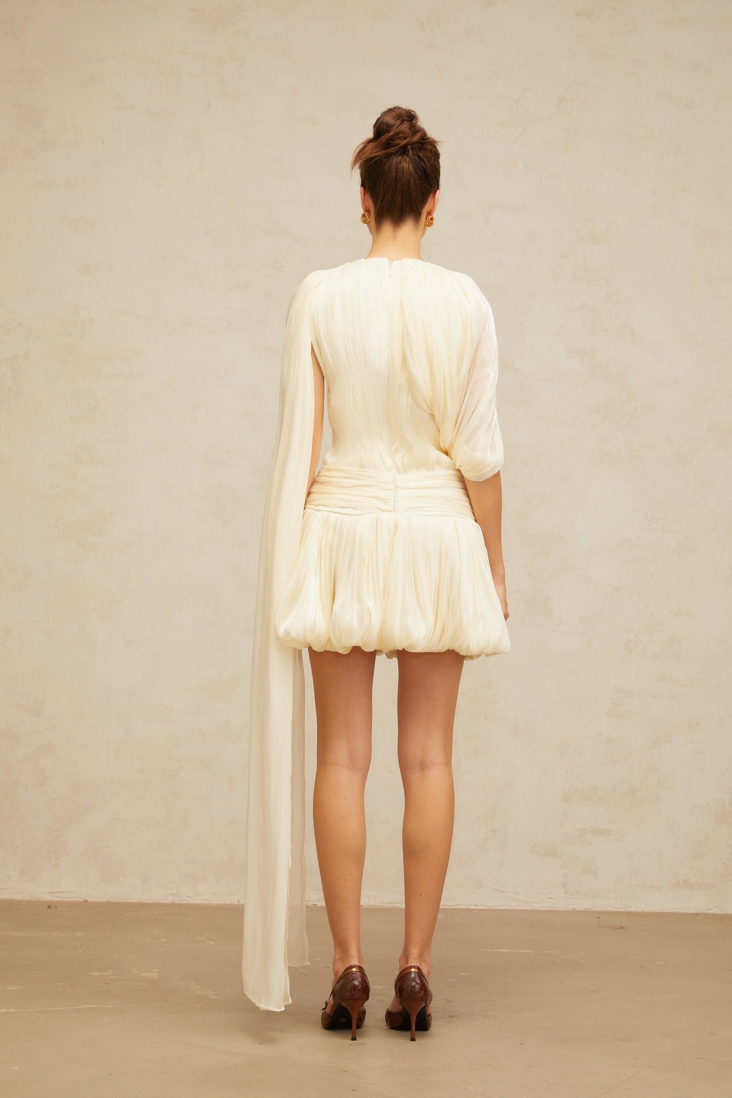 Woman wearing short pleated dress with ribbon accent at waist flared skirt and sleeveless design