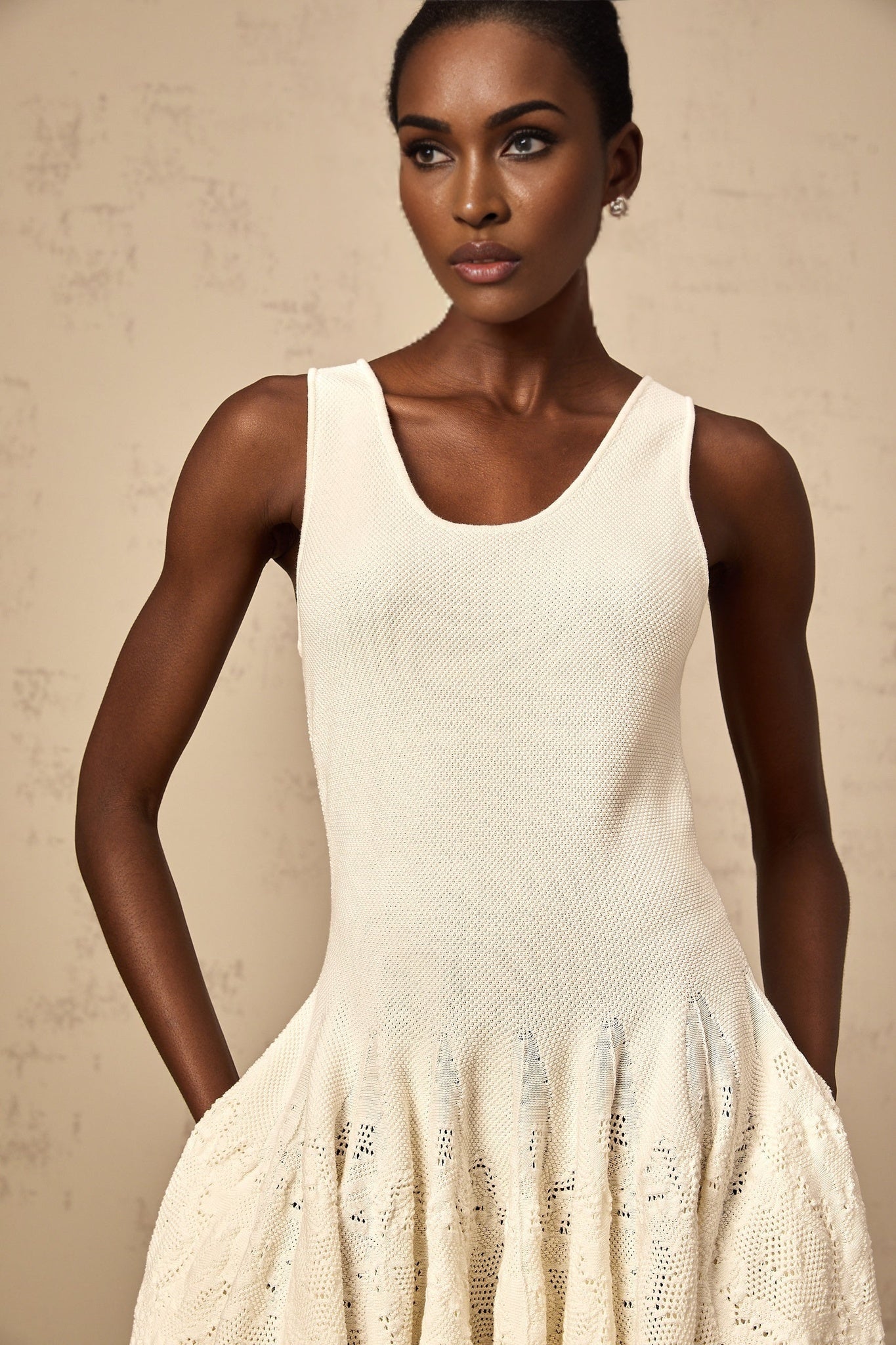 Woman wearing short white textured knit dress with floral pattern and long sleeves