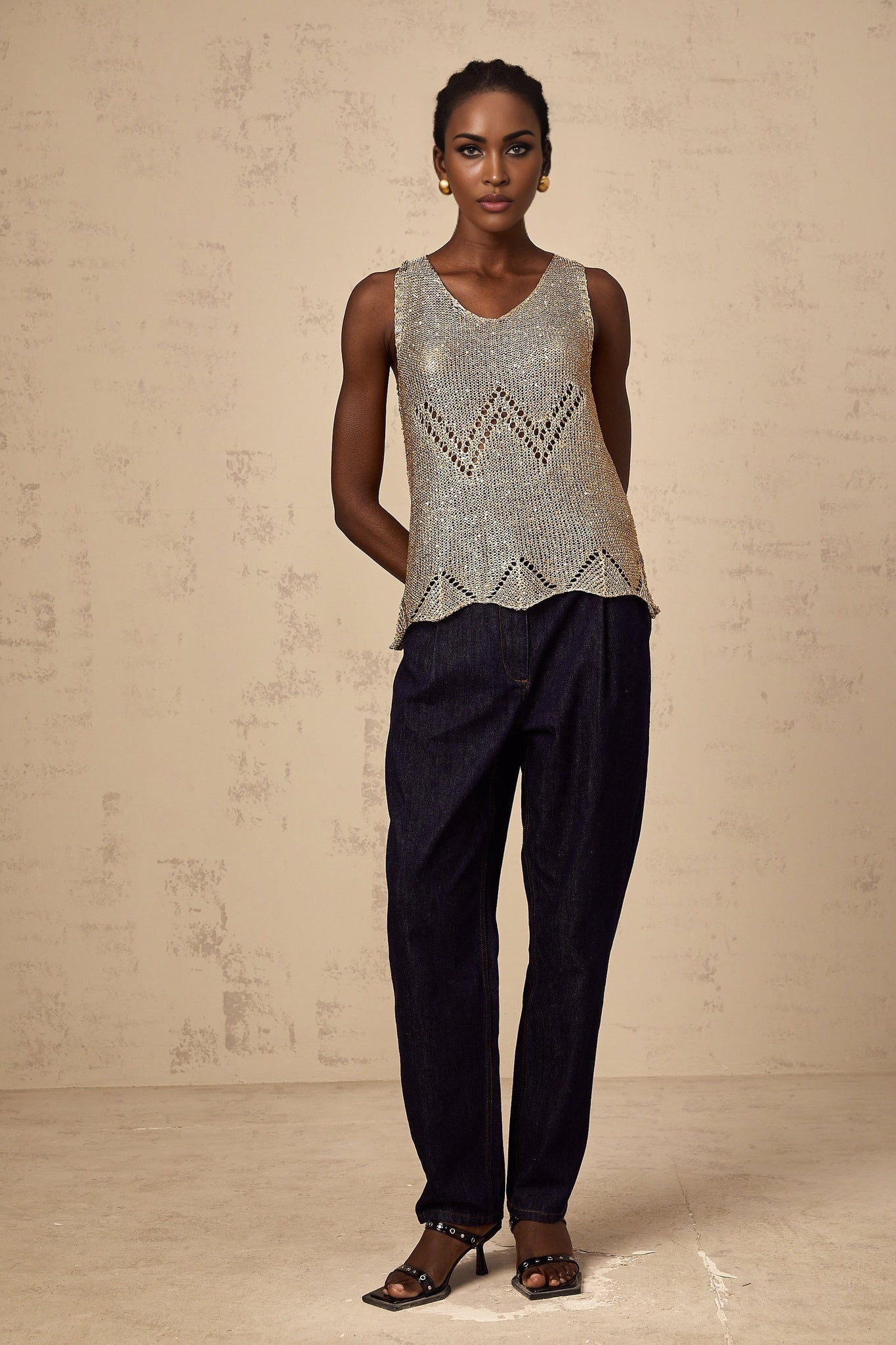 Woman wearing sleeveless gold vest top with sequins and crochet design