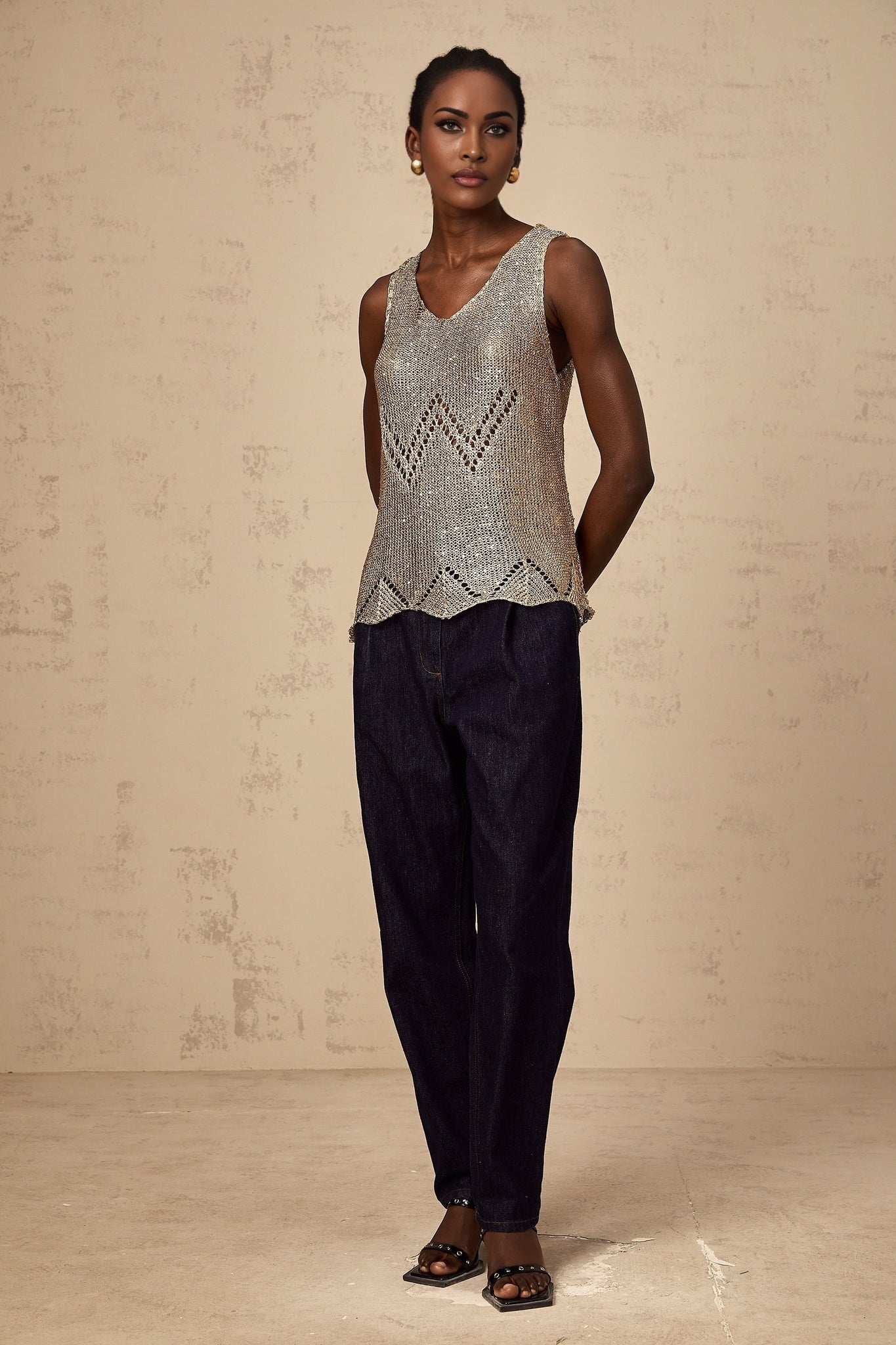 Woman wearing sleeveless gold vest top with sequins and crochet design