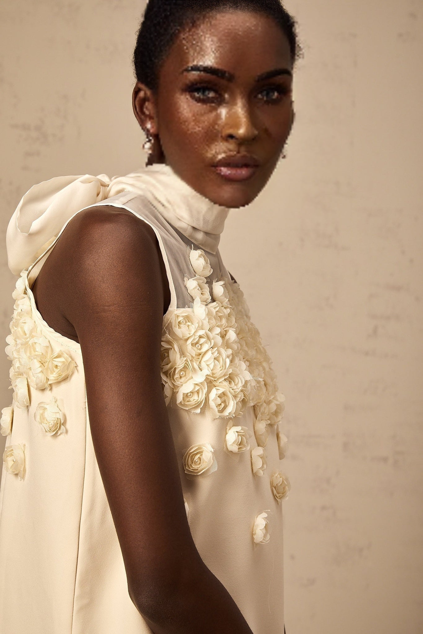 Woman wearing sleeveless mini dress with floral pattern standing against plain background