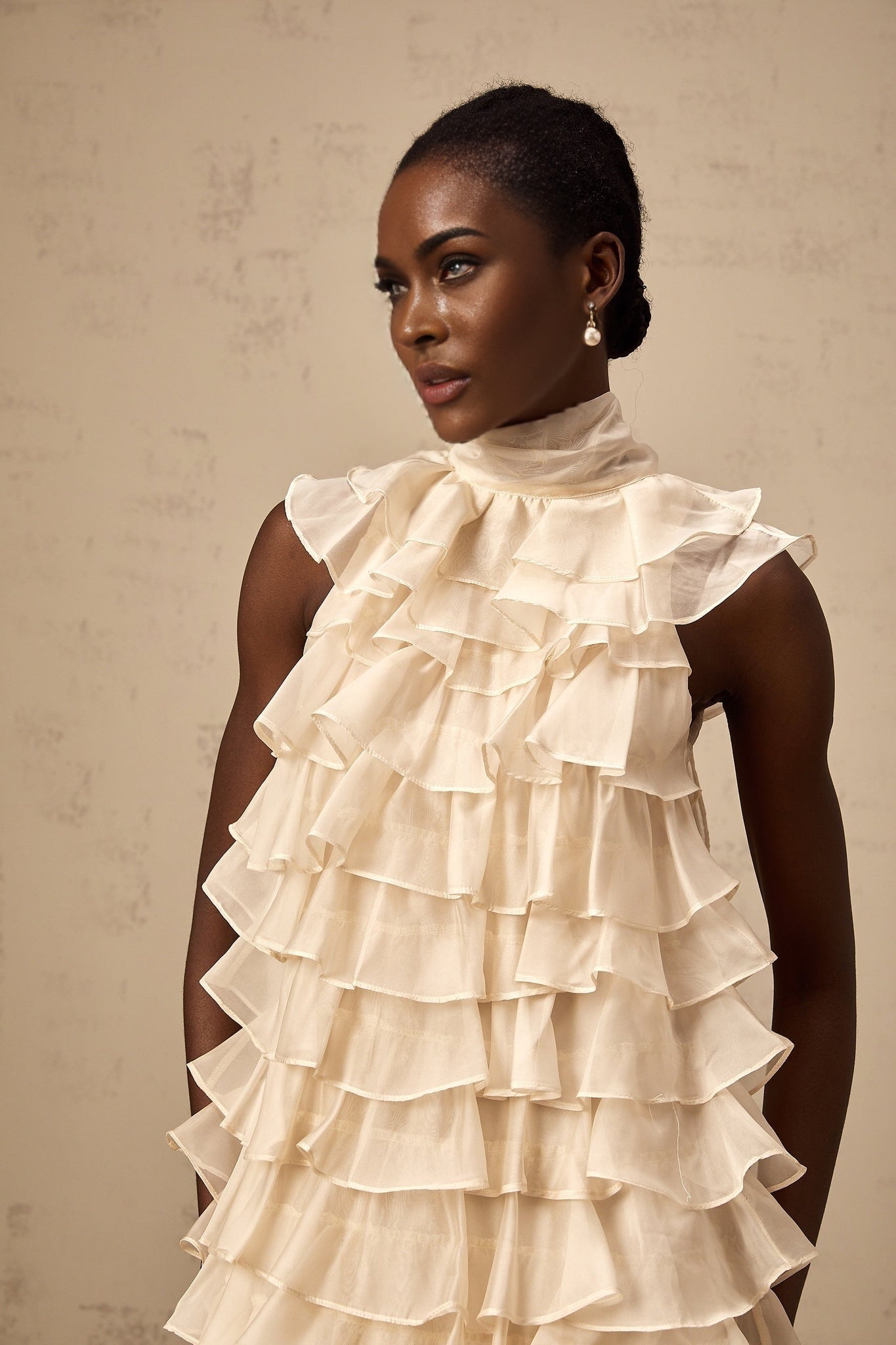 Woman wearing sleeveless mini dress with tiered flounce design in light fabric
