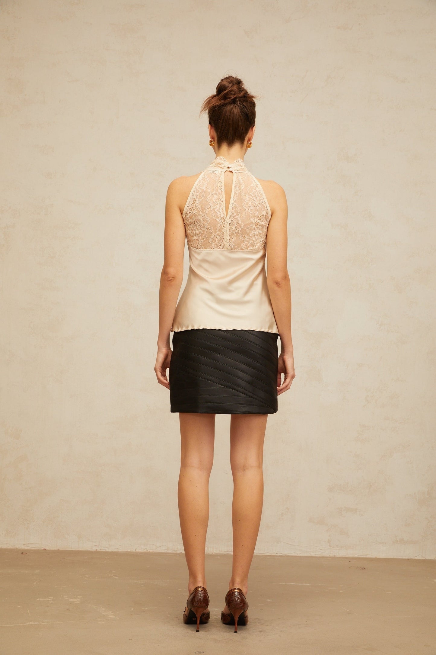 Woman wearing sleeveless satin top with floral lace panels in neutral color