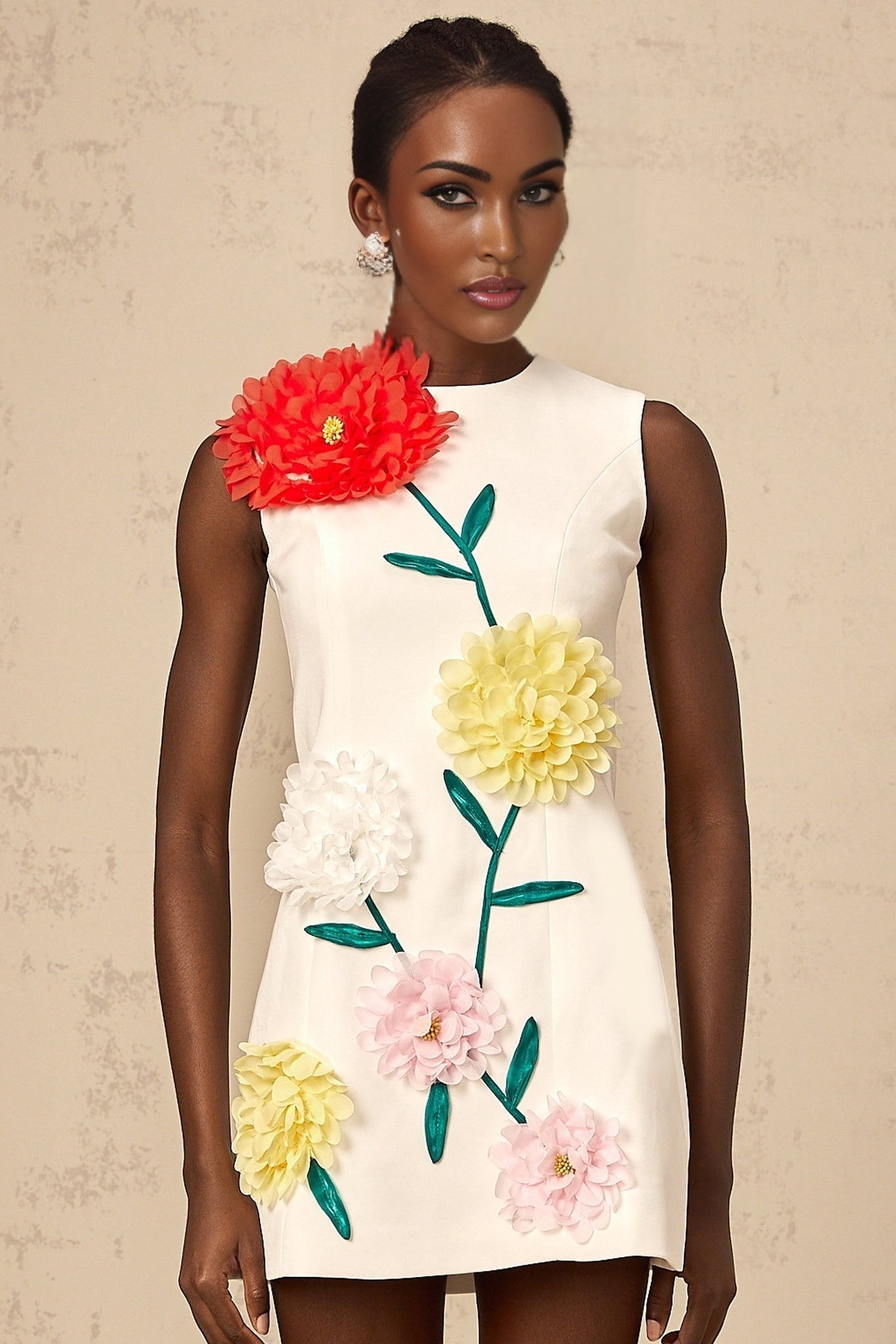 Woman wearing sleeveless white mini dress with three dimensional floral petal details