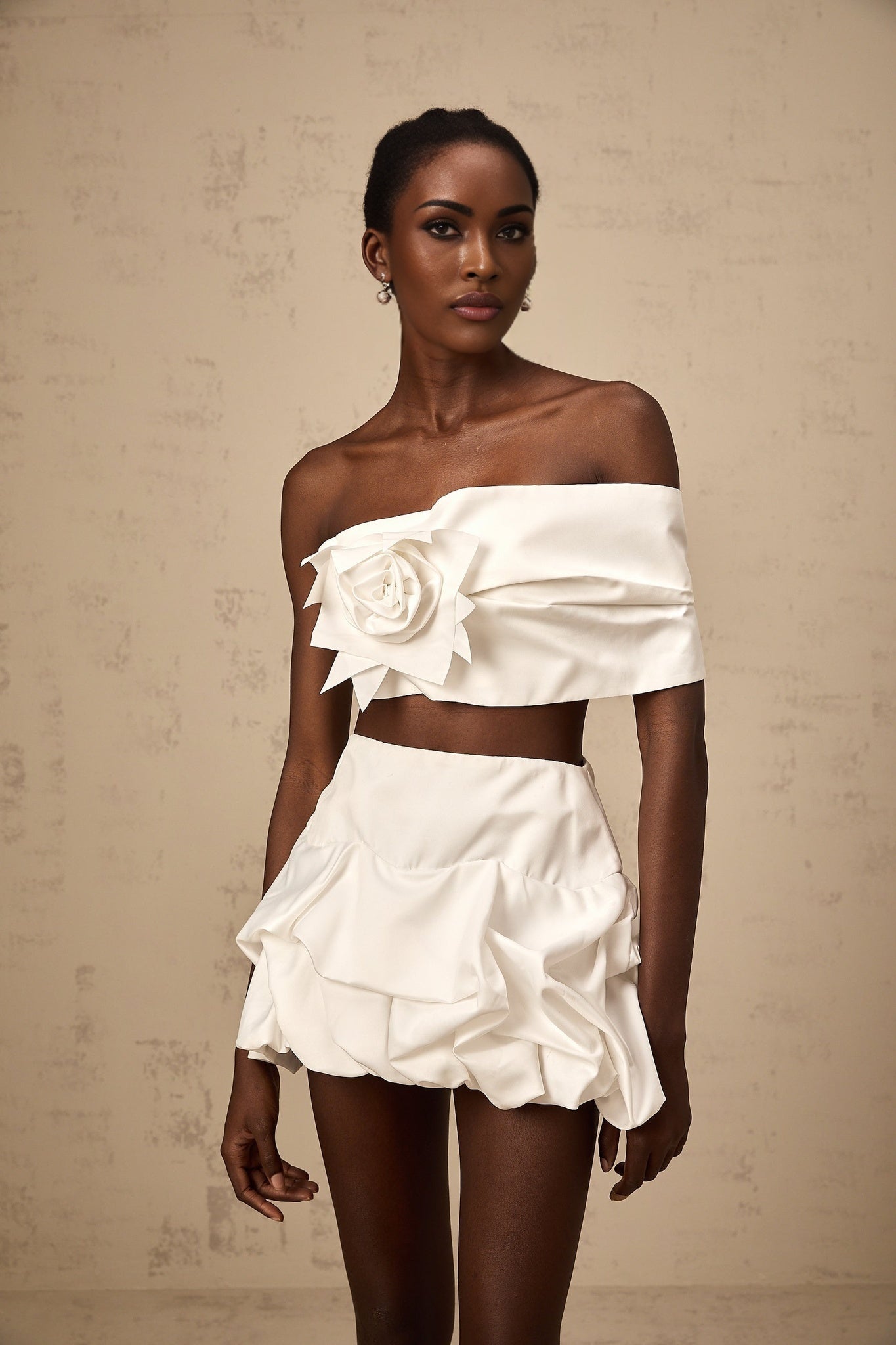 Woman wearing white floral pleated top and matching skirt set by Honorine standing against plain background