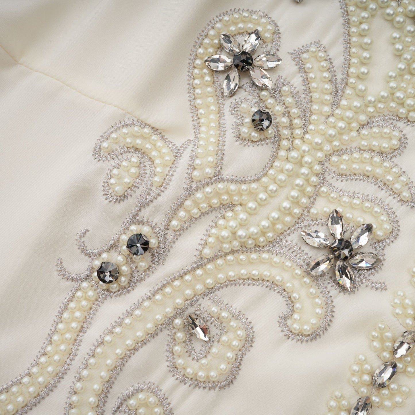 Woman wearing white jacket and dress set with pleated details and embellishments