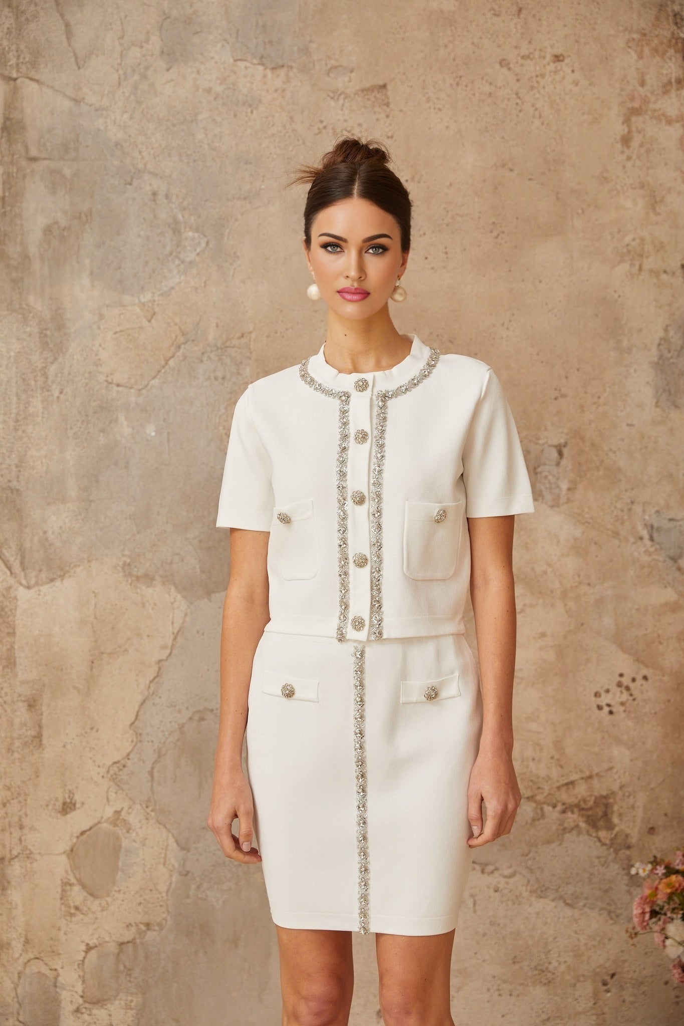 Woman wearing white knit top and skirt set with crystal embellishments