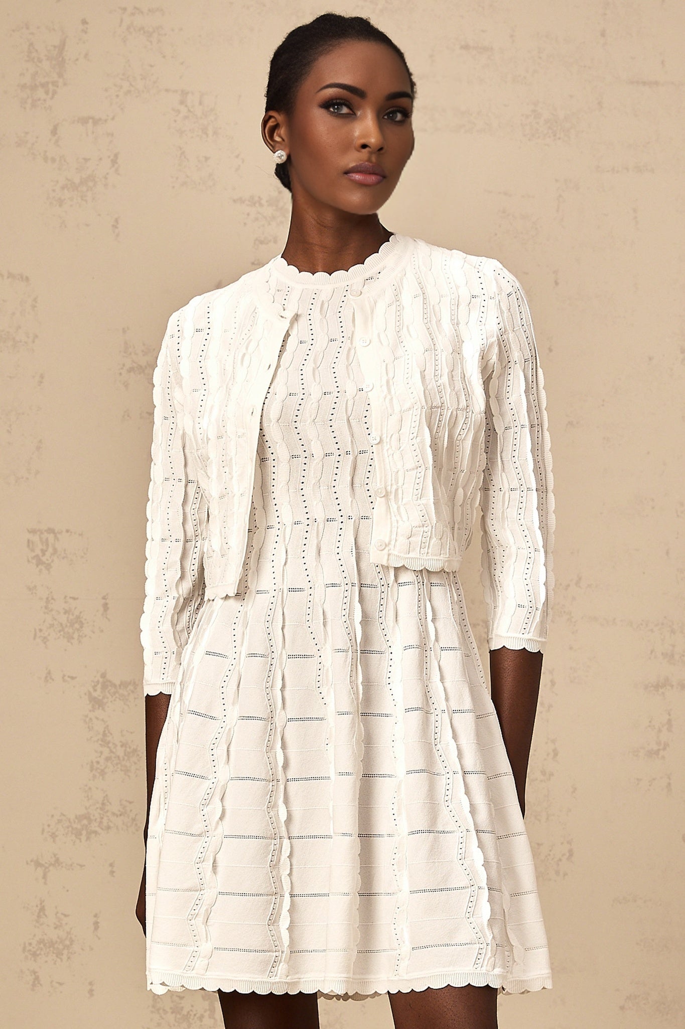 Woman wearing white knitted cardigan with ruffled details and button front