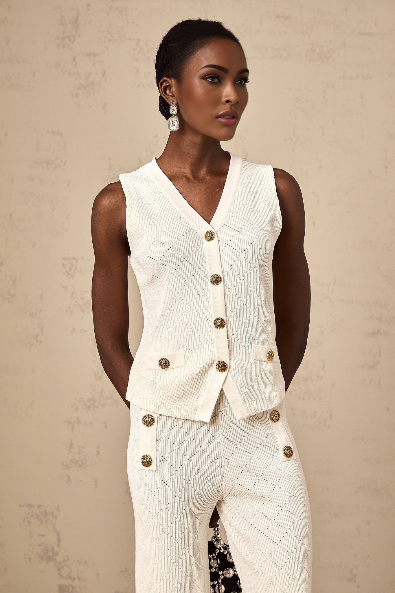 Woman wearing white knitted top and matching trousers lounging comfortably on sofa