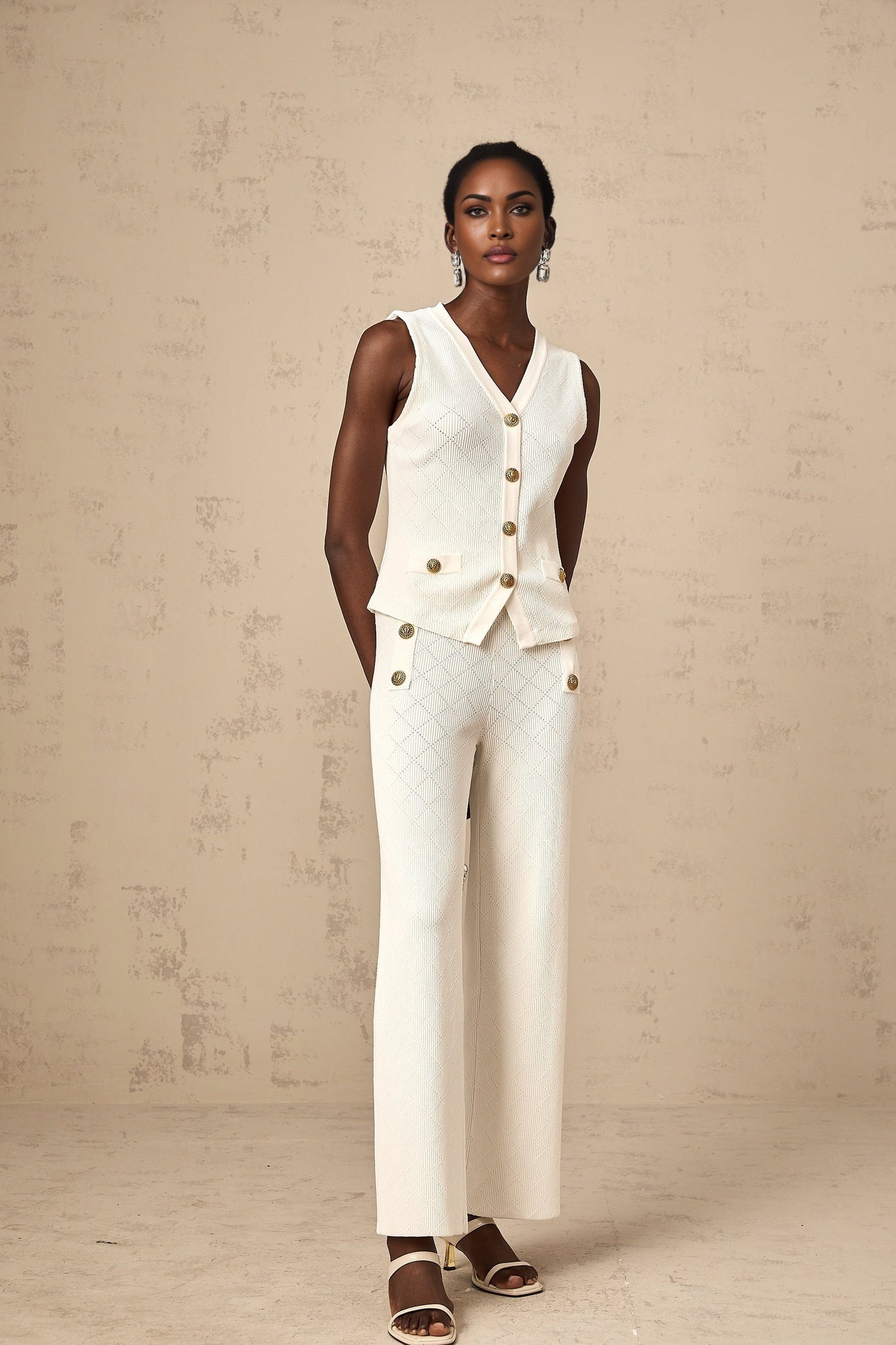 Woman wearing white knitted top and matching trousers set standing in relaxed pose