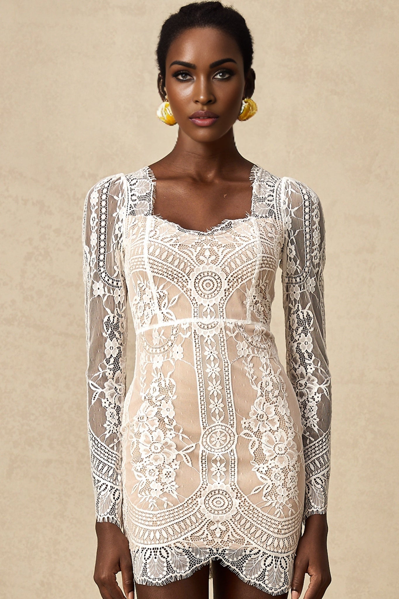 Woman wearing white lace mini dress with scalloped hem and short sleeves standing against plain background