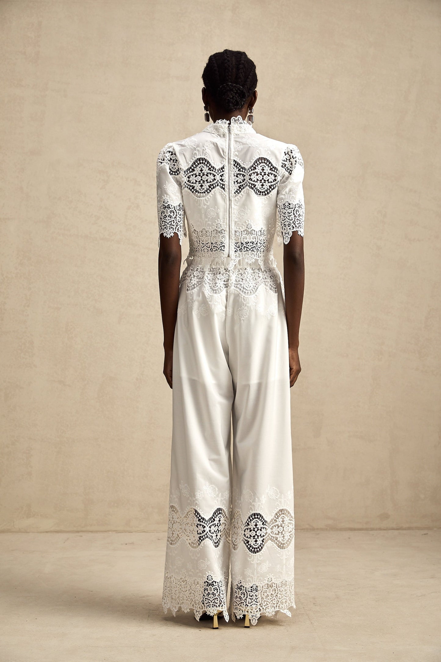 Woman wearing white lace trim cropped top and matching trousers with cutout details Raphaelle matching set