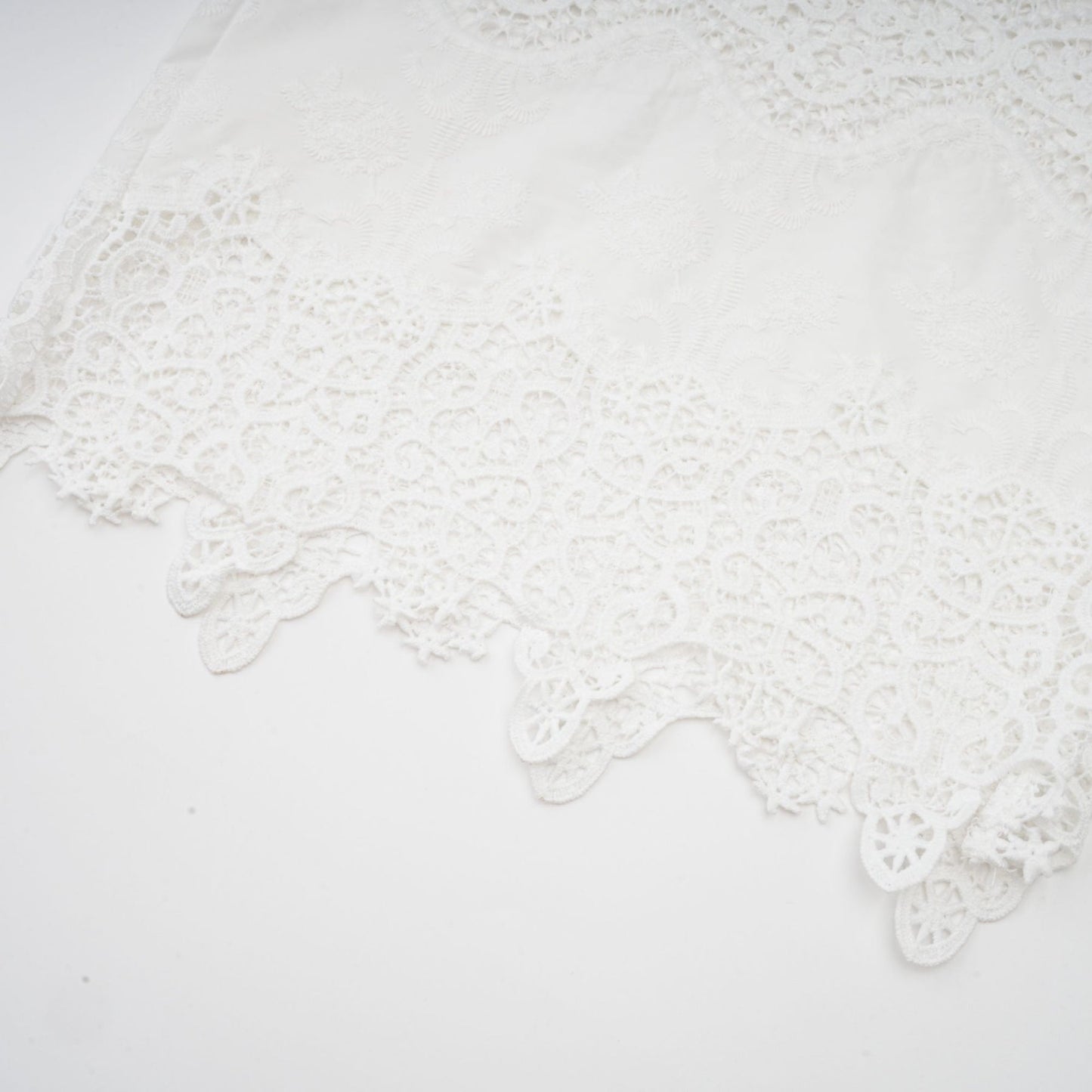 Woman wearing white lace trim cropped top and matching trousers with cutout details Raphaelle matching set
