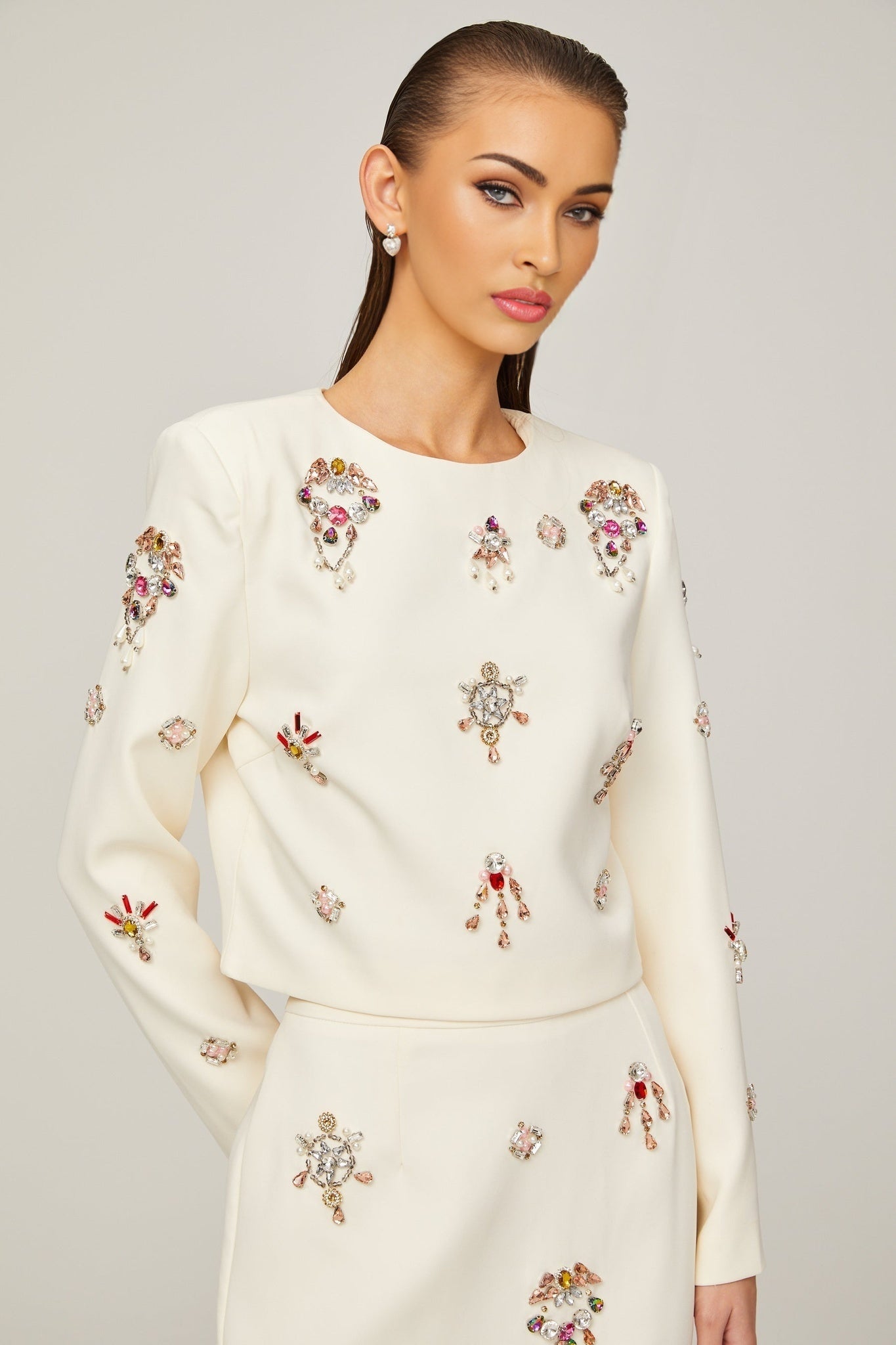 Woman wearing white matching set consisting of a crystalembellished top and skirt named Jeanne