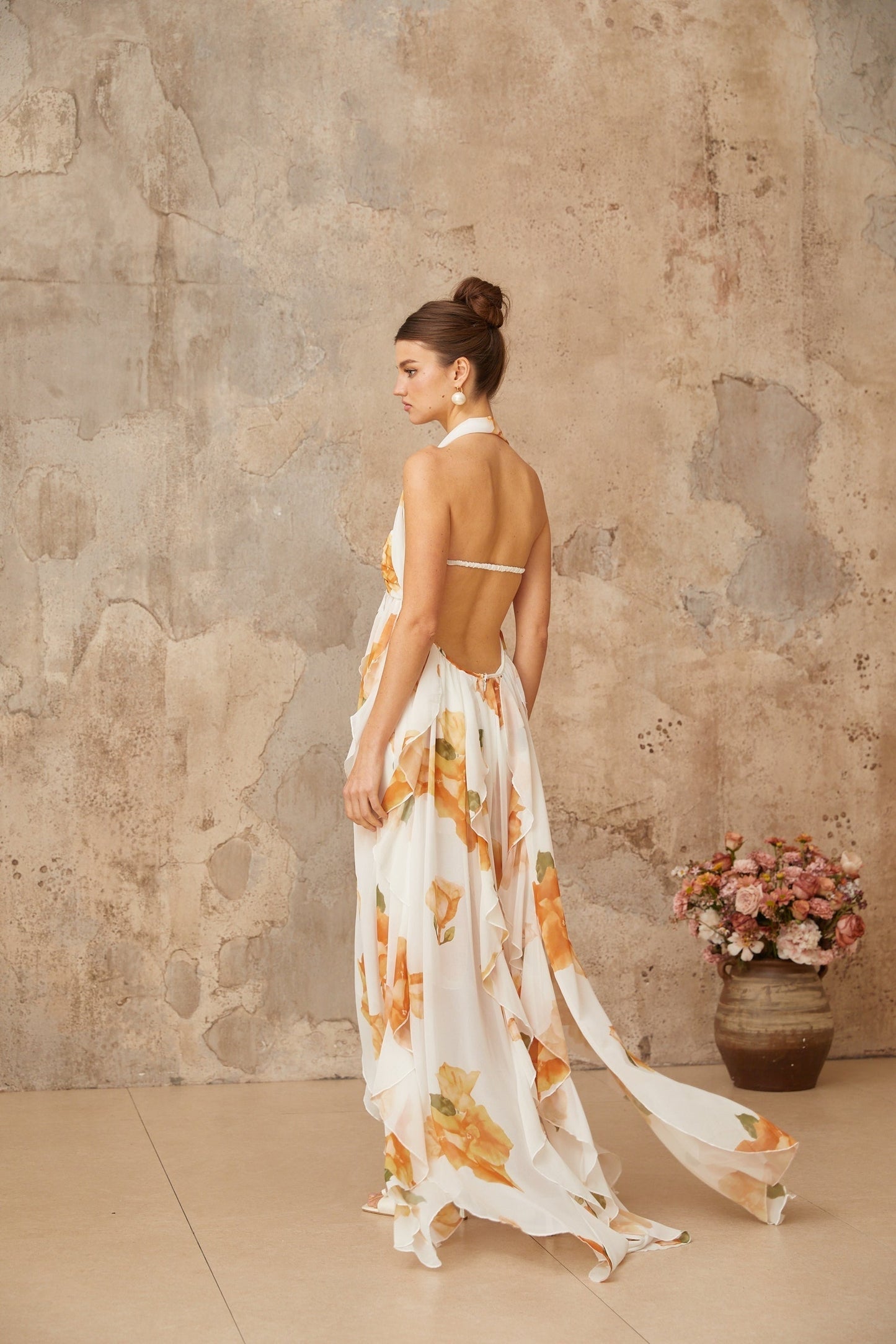 Woman wearing white maxi dress with floral print and ruffled tulle details standing in outdoor setting