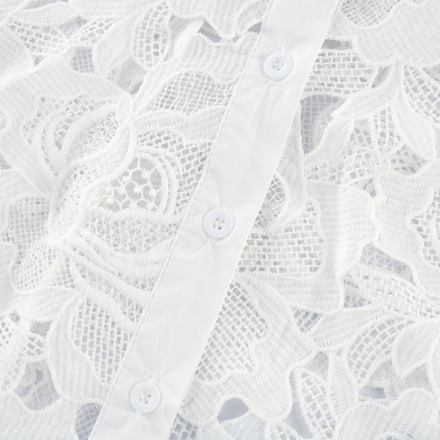 Woman wearing white midi dress with floral embroidery details standing against plain background