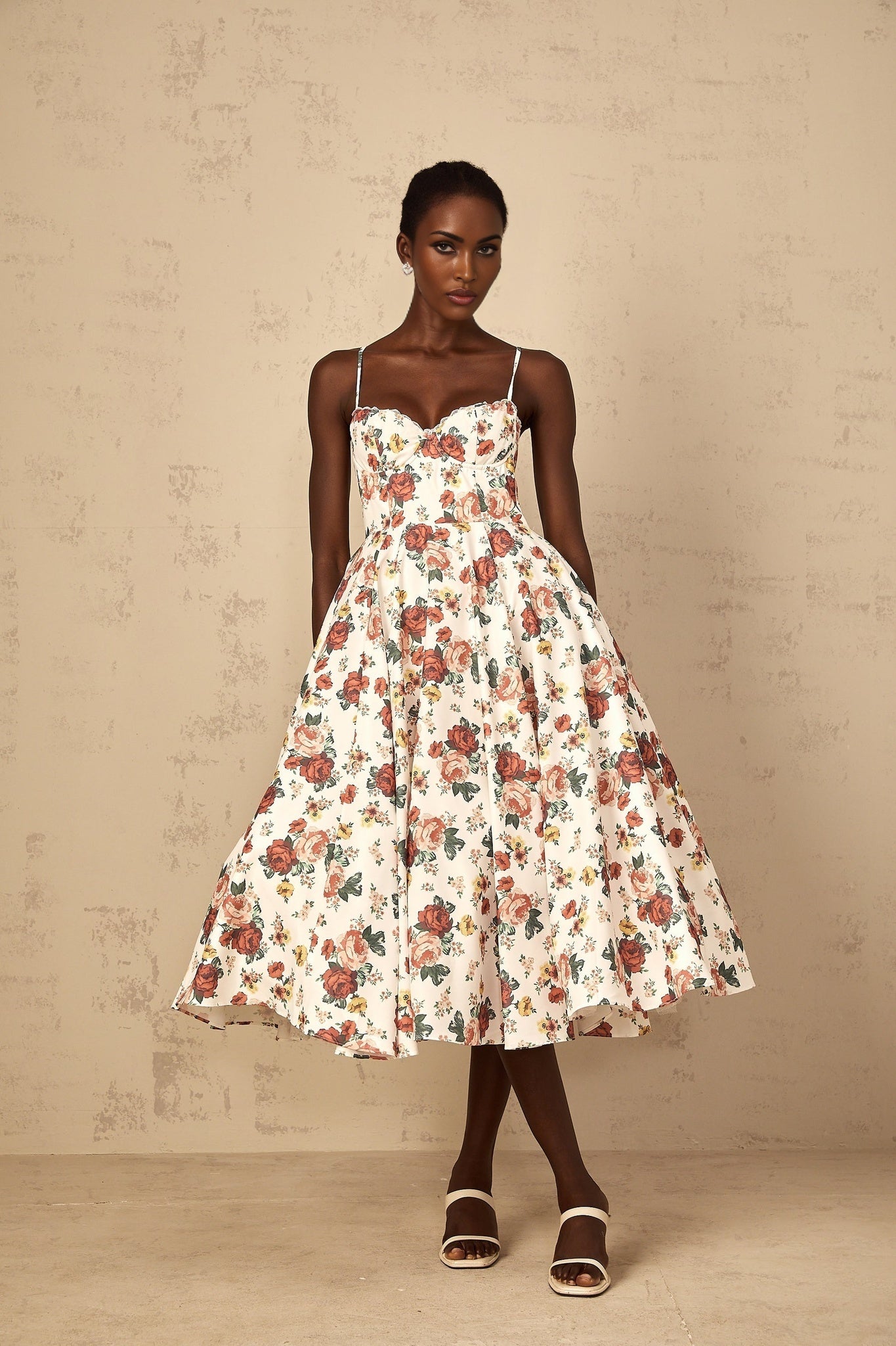 Woman wearing white midi dress with rose print pattern and flounced details
