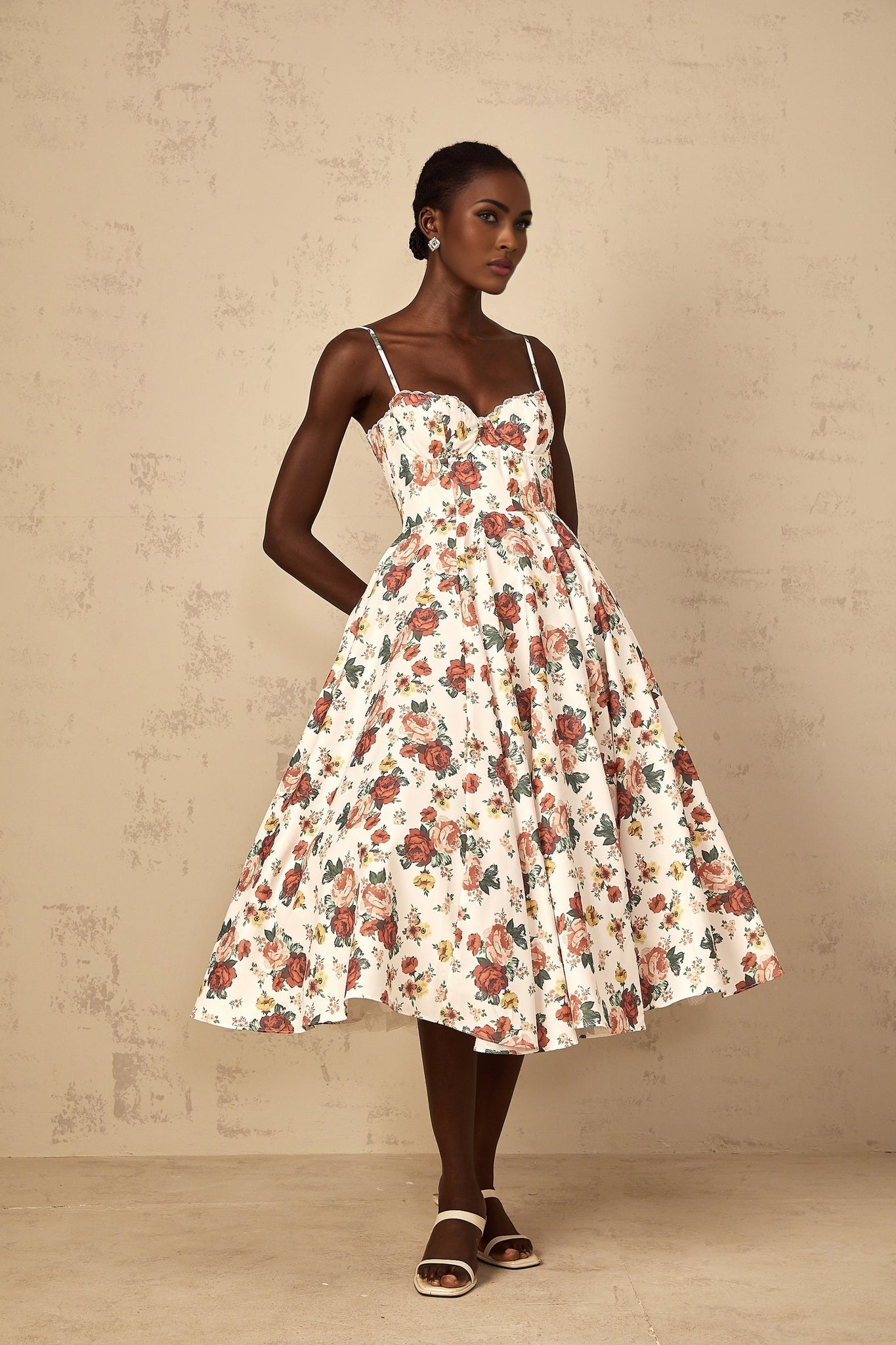 Woman wearing white midi dress with rose print pattern and flounced details
