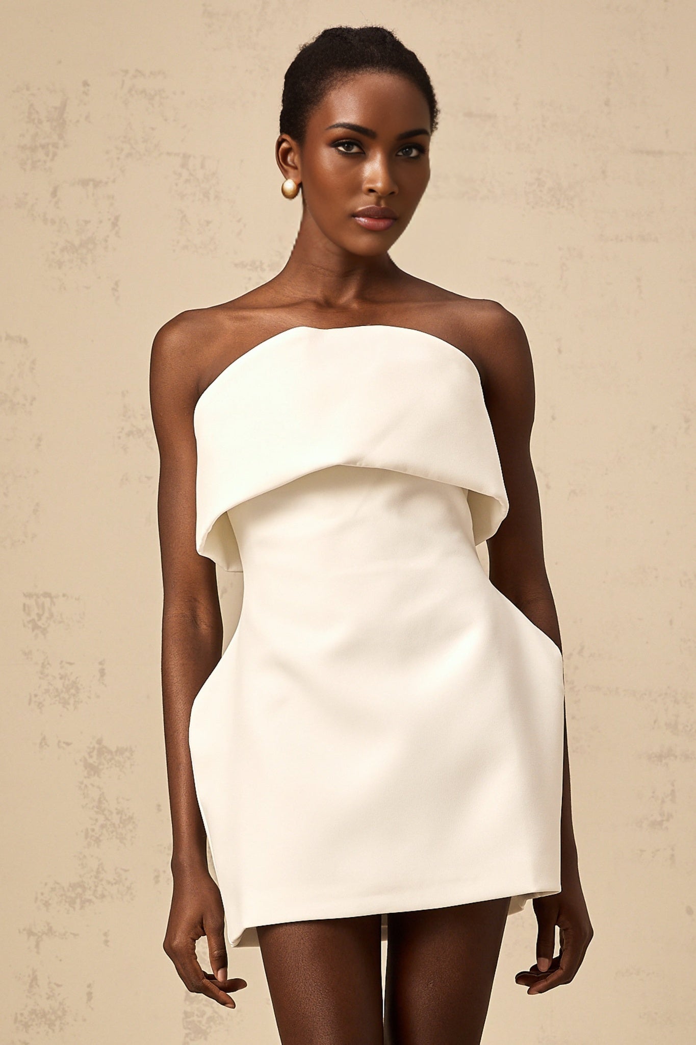 Woman wearing white off shoulder mini dress with puff sleeves against plain background