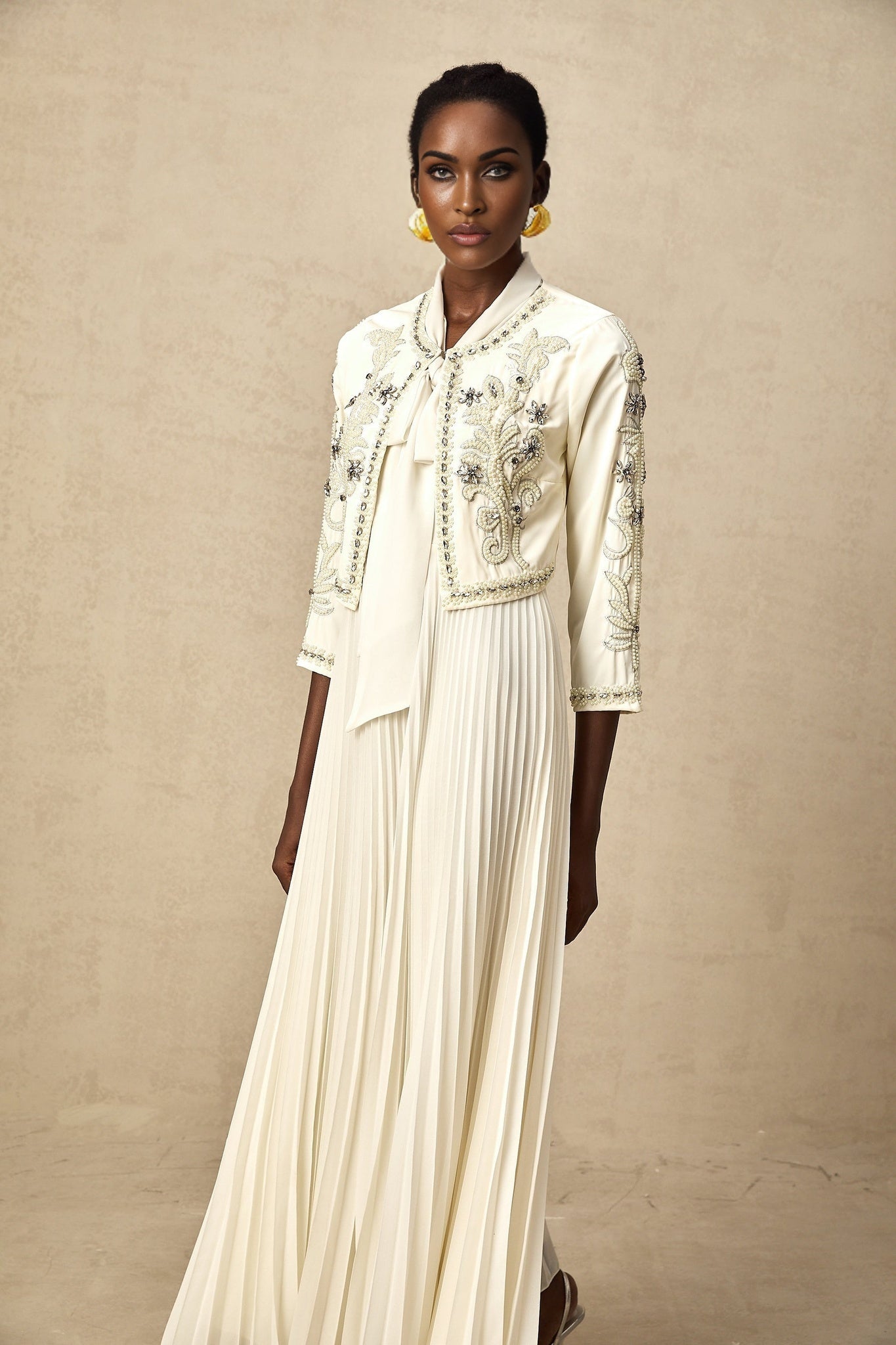 Woman wearing white pleated jacket and dress set with embellishments Blanche design elegant formal outfit