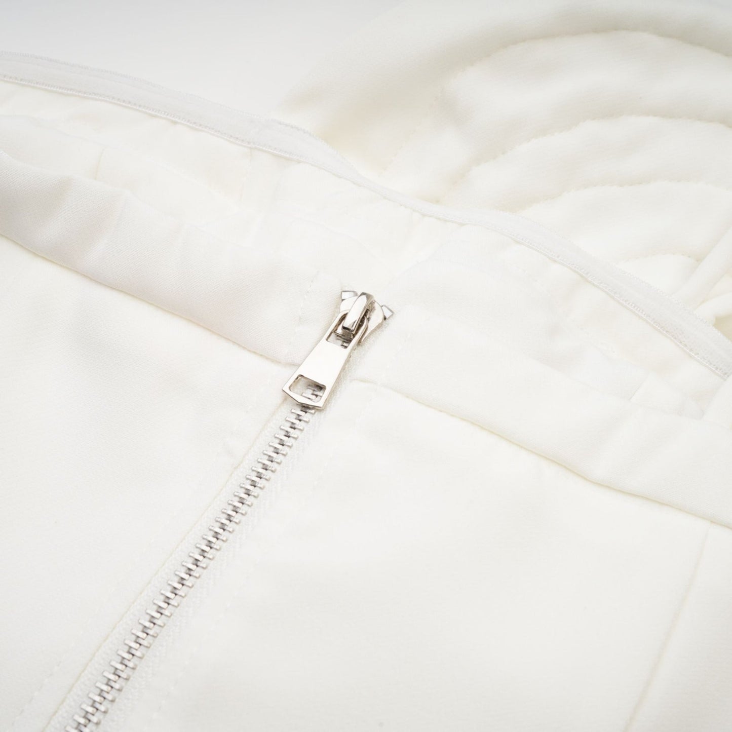 Woman wearing white sleeveless top with delicate floral applique details on the bodice
