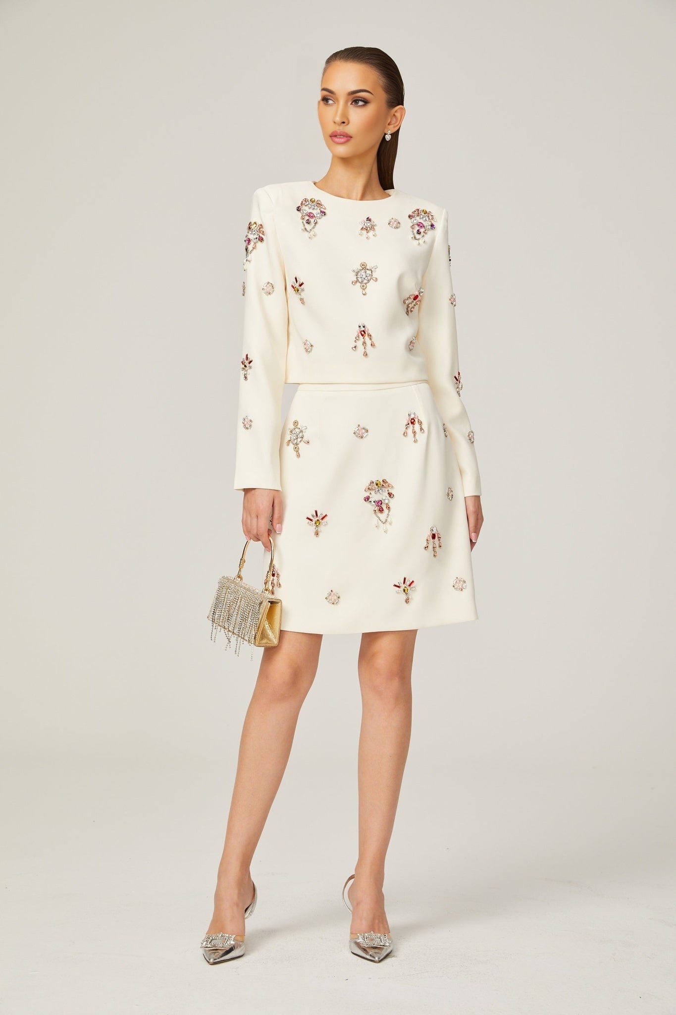 Woman wearing white top and skirt set adorned with crystal embellishments