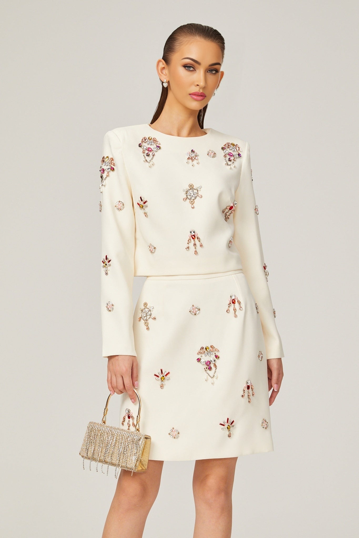 Woman wearing white twopiece outfit featuring crystal embellishments top and skirt set named Jeanne