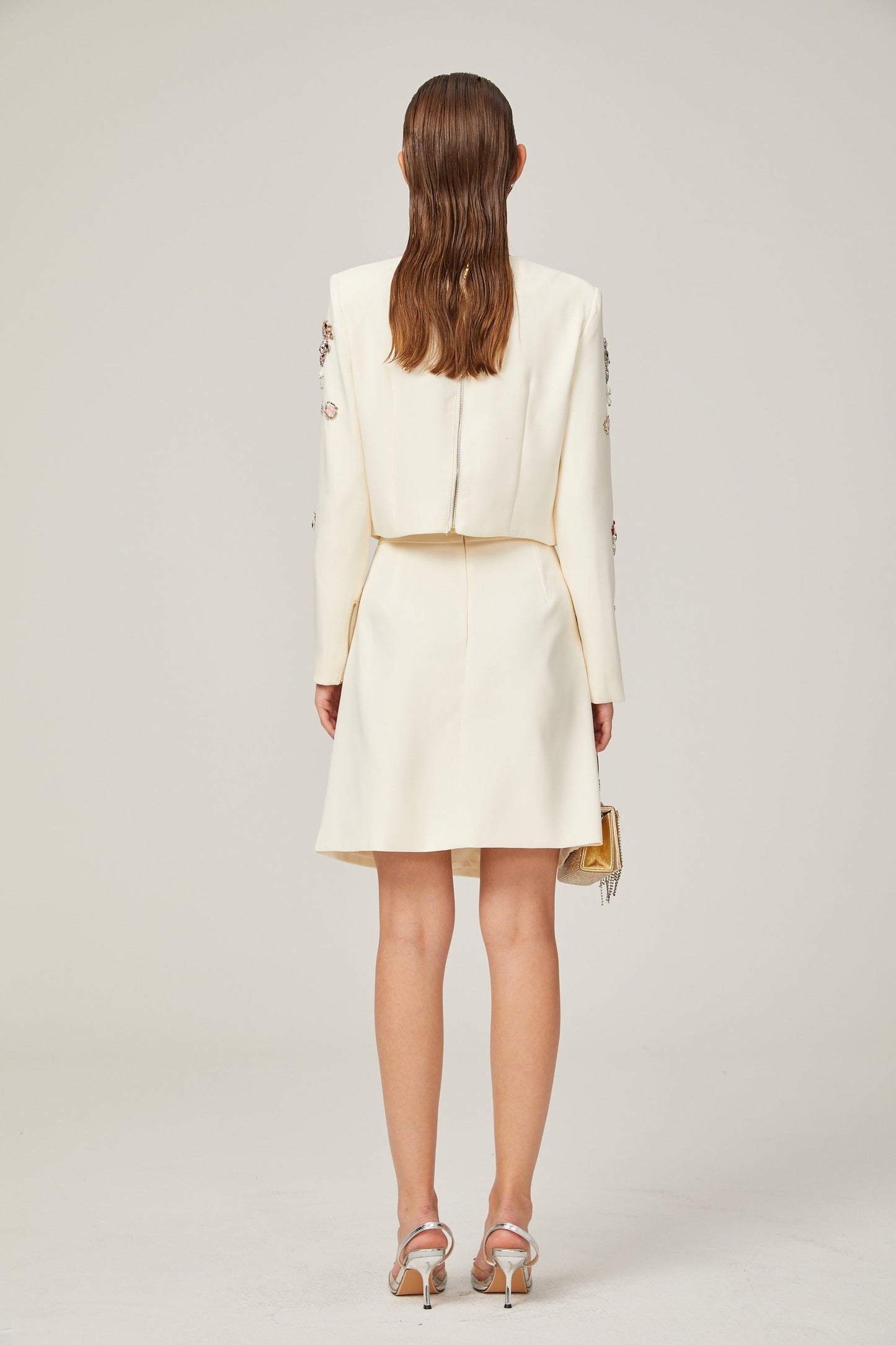 Woman wearing white twopiece outfit with crystal embellishments top and skirt set named Jeanne