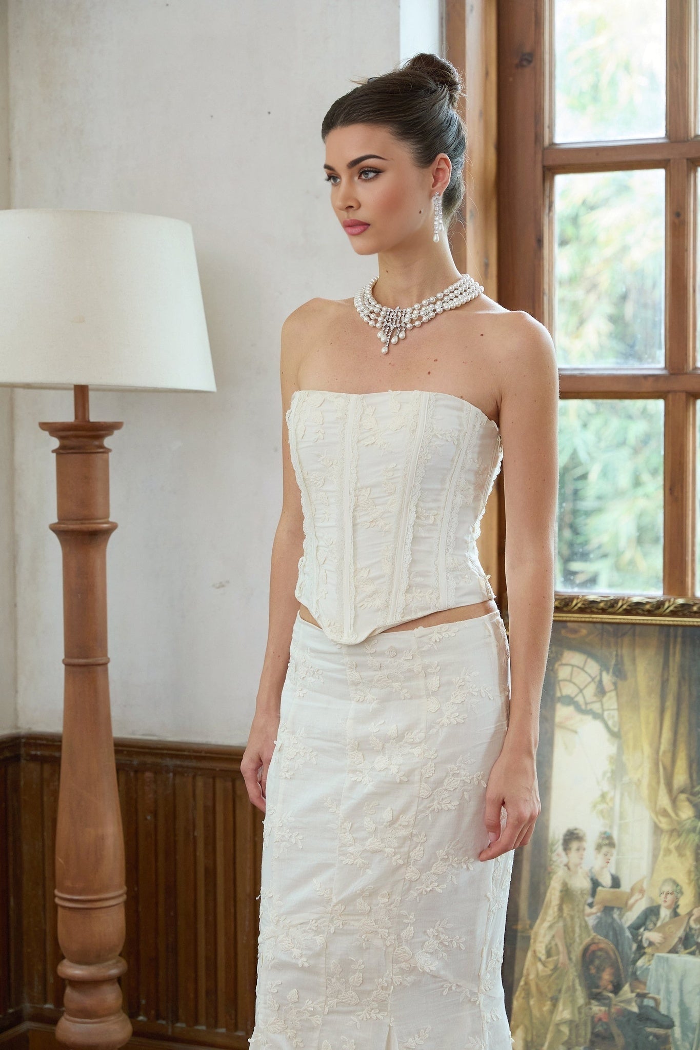 Woman wearing white twopiece outfit with embroidery details matching top and skirt set called Margot