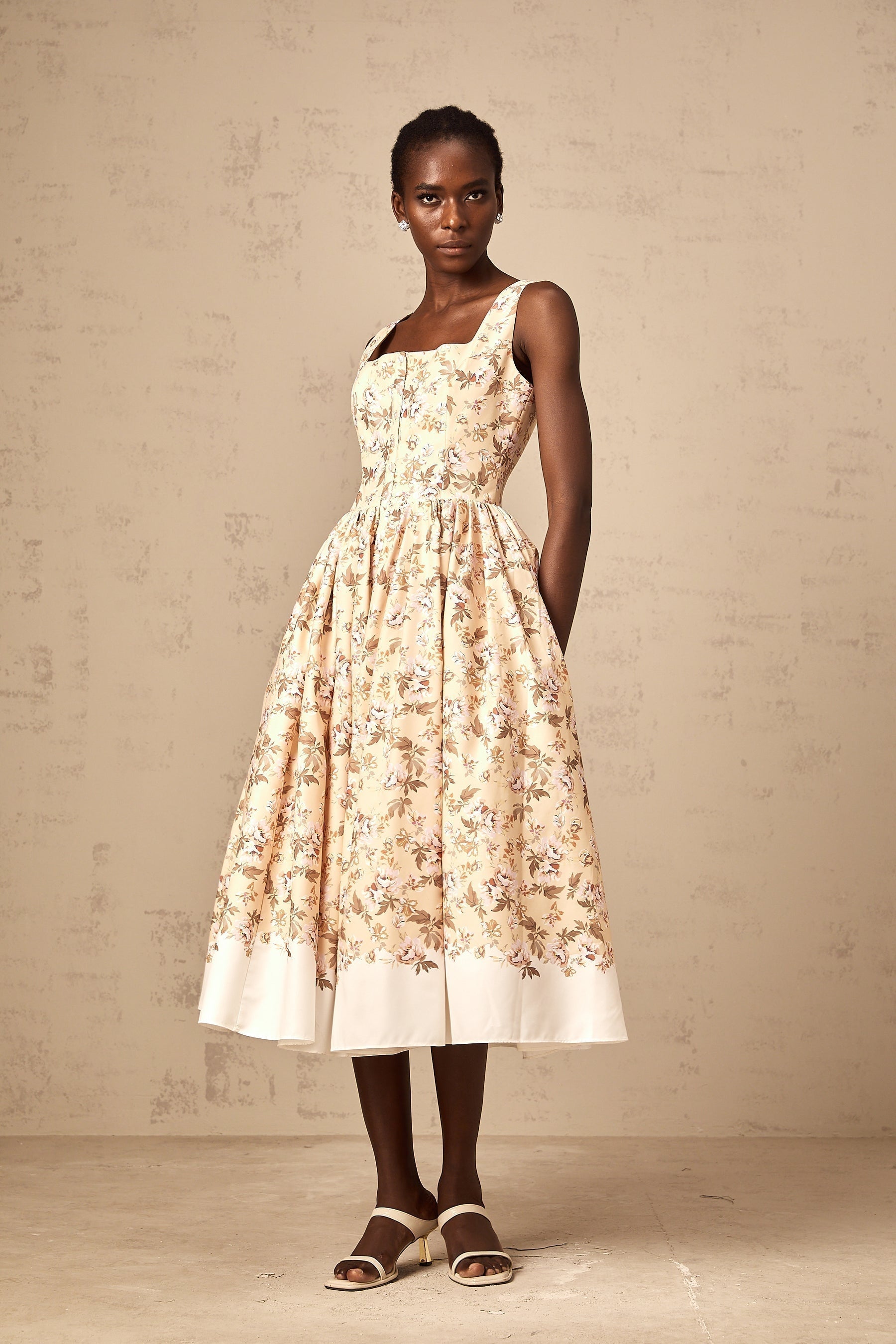 Woman wearing yellow midi dress with floral print and button details