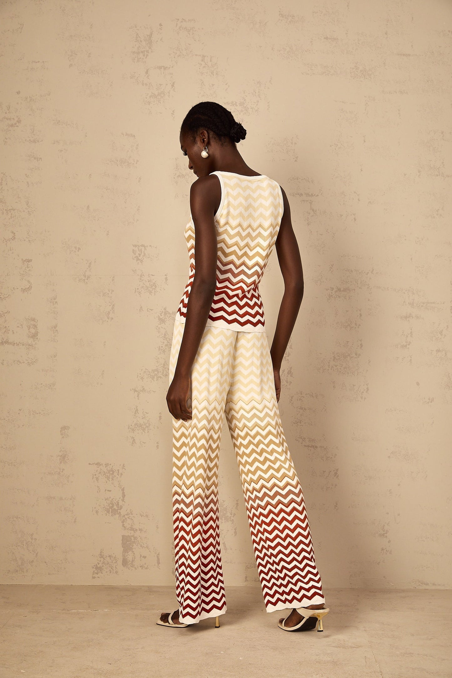 Woman wearing yellow zigzag knit two piece set consisting of top and bottoms