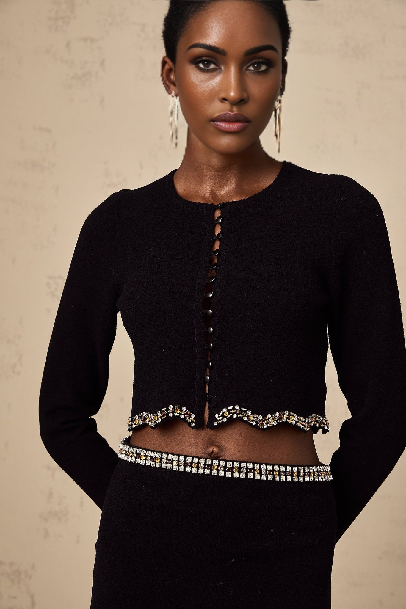 Womans black knitted matching set with cardigan and skirt featuring embellished details