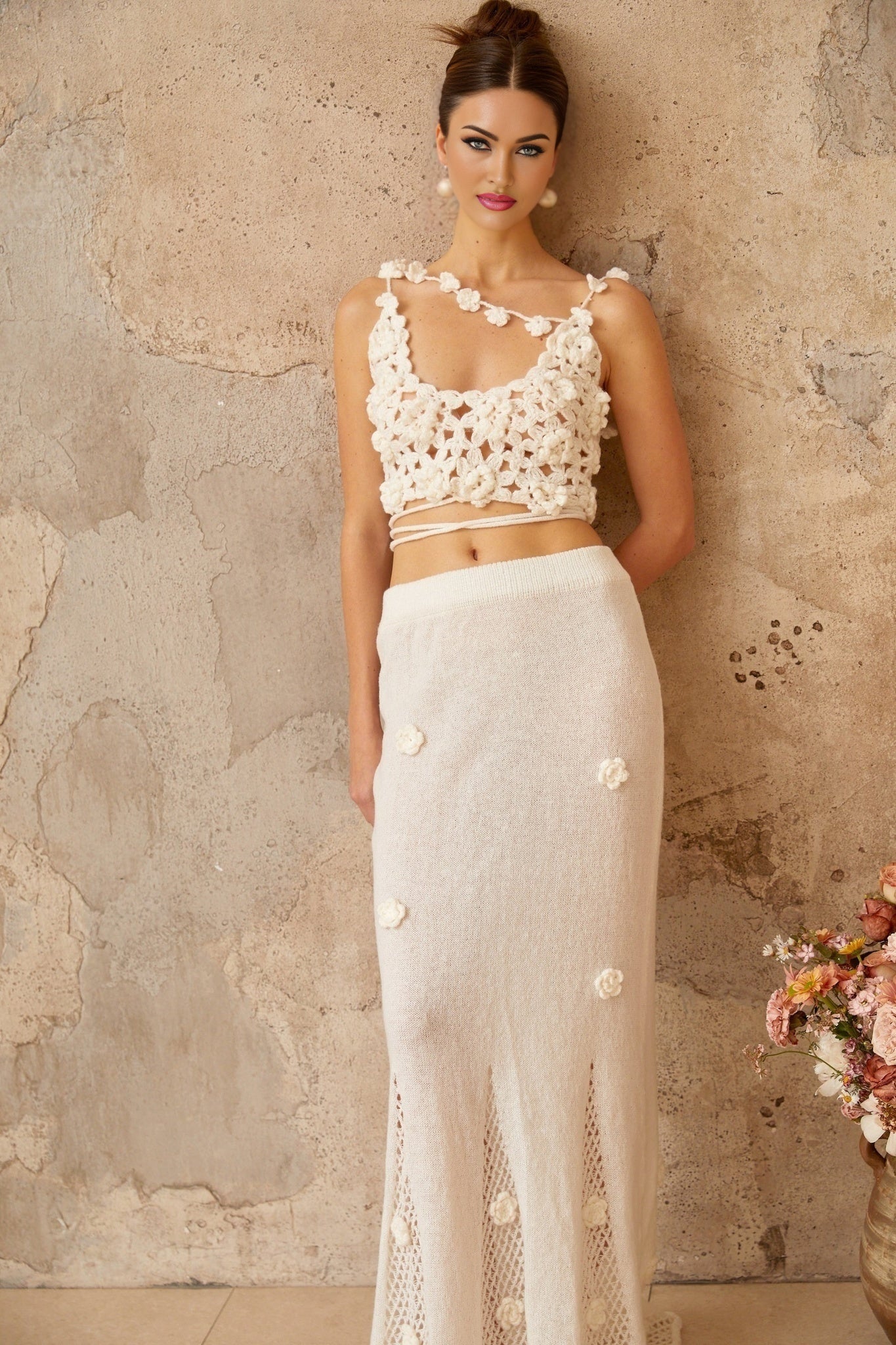 Womans white two piece outfit with floral applique design top and matching skirt on plain background