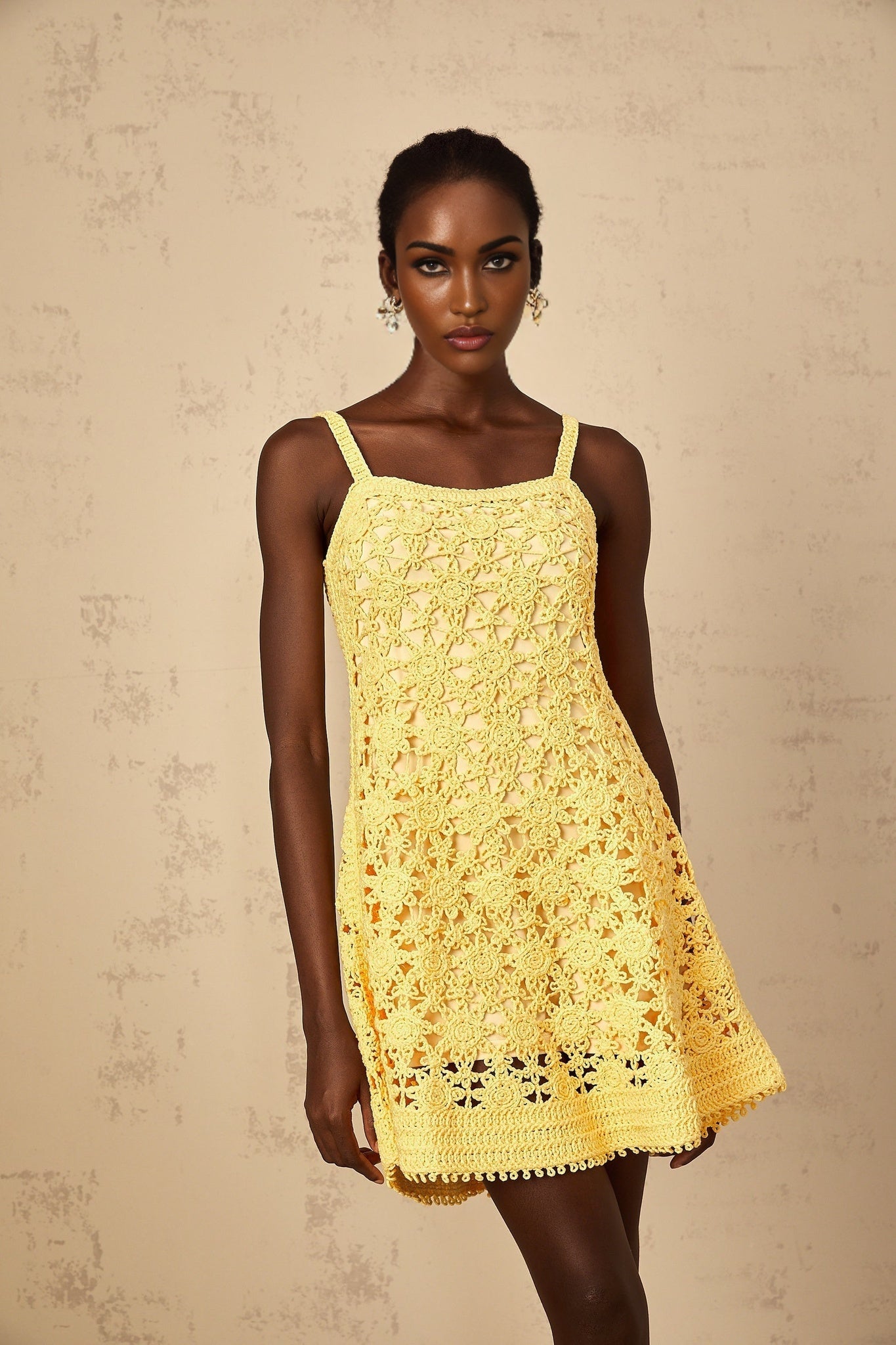 Yellow crocheted mini dress with flared skirt and short sleeves on female model