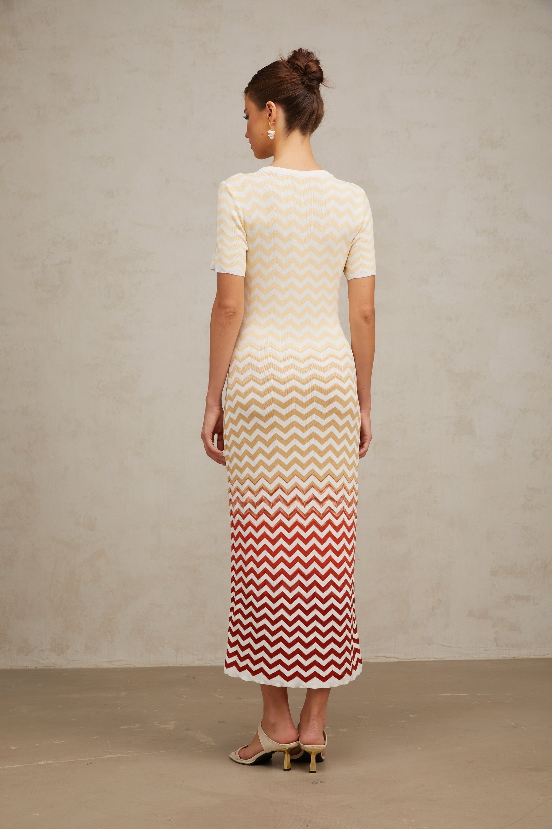 Yellow zigzag patterned knit midi dress with long sleeves on a white background