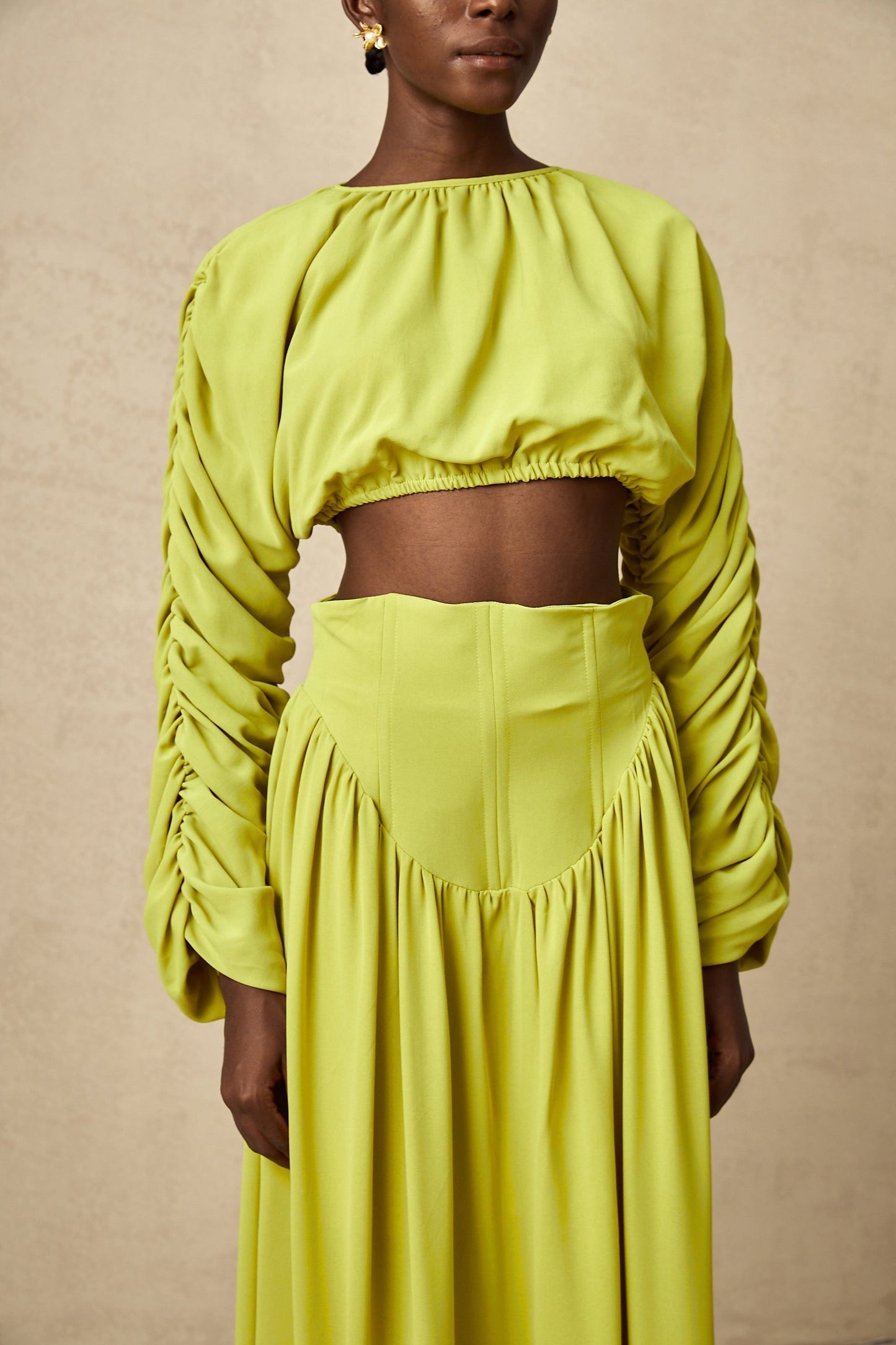 Young girl wearing a green smocked top and matching skirt set called Emilie