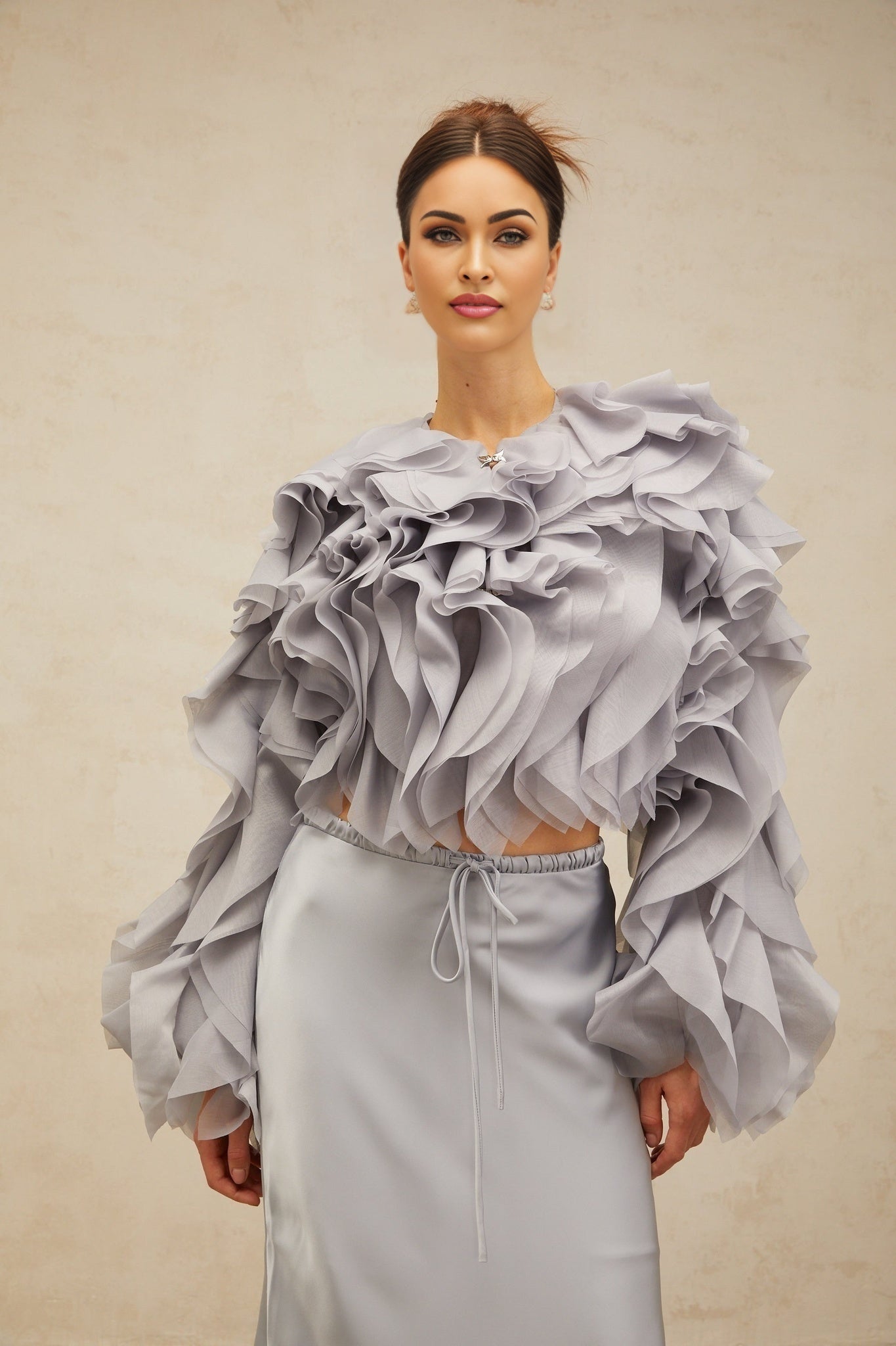 Young girl wearing a light blue matching set consisting of a blouse with a bow and ruffles paired with a coordinating skirt