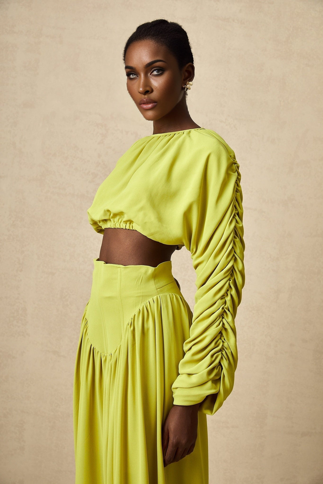 Young girl wearing a matching green smocked top and skirt set named Emilie featuring a floral pattern and ruffle details