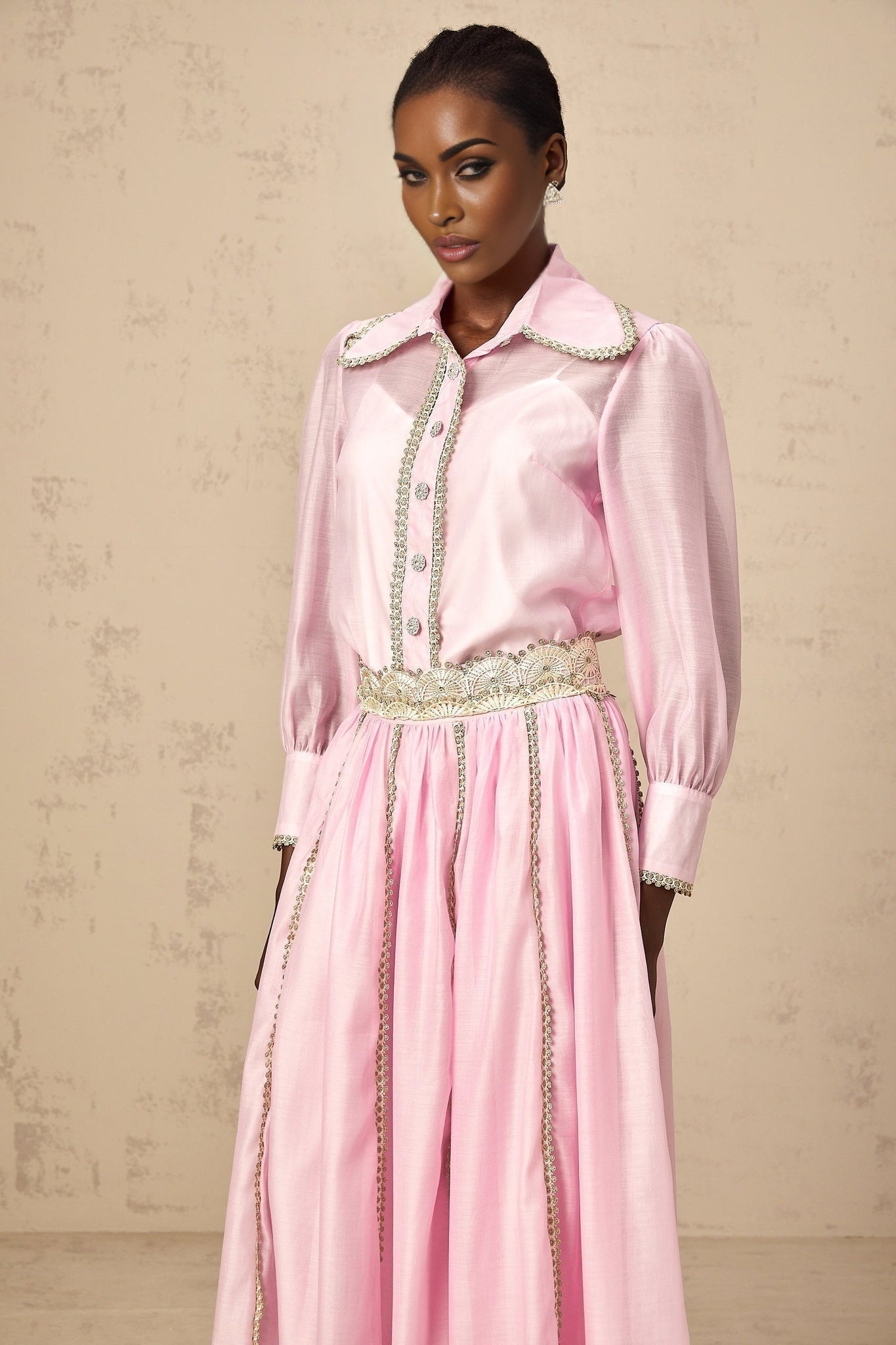 Young girl wearing a pink lace trimmed shirt and matching skirt set by Frida