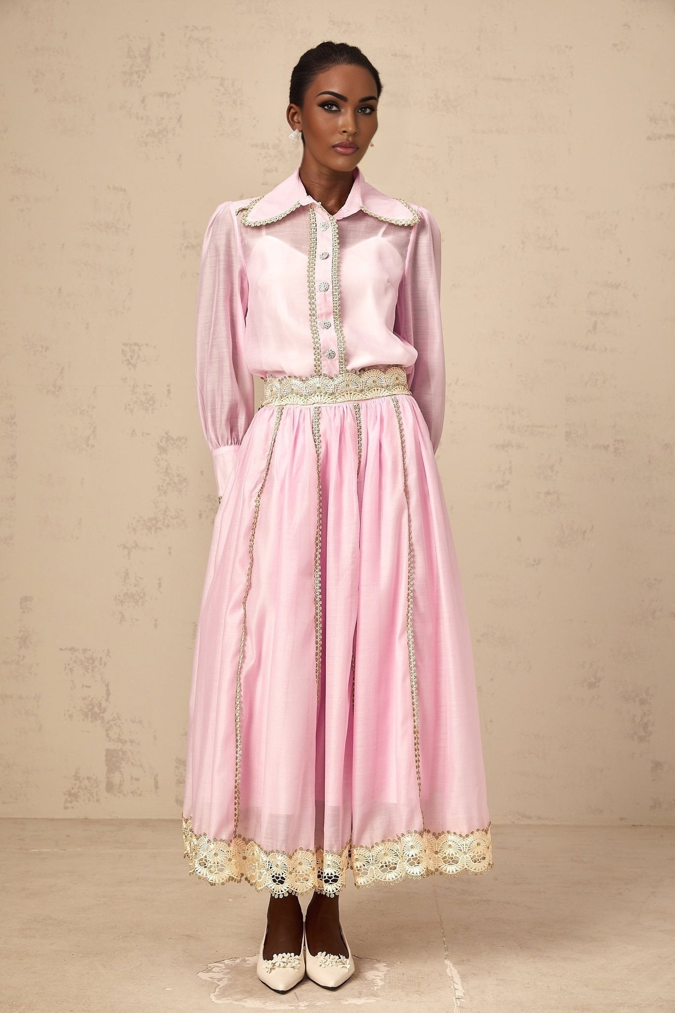 Young girl wearing a pink matching set with lace trim shirt and skirt Frida style