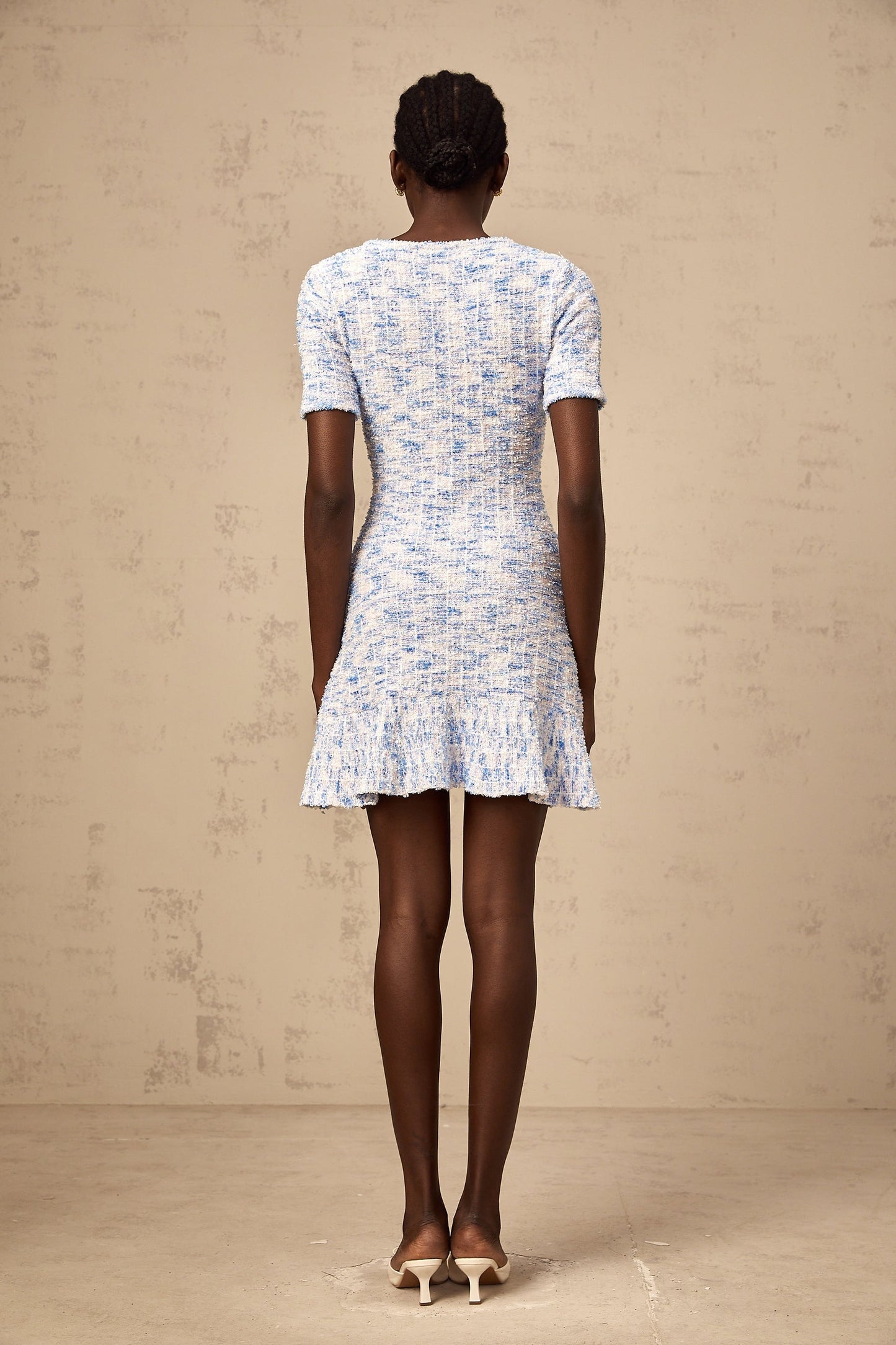 Young woman wearing a blue checked knit mini dress with short sleeves and a fitted silhouette
