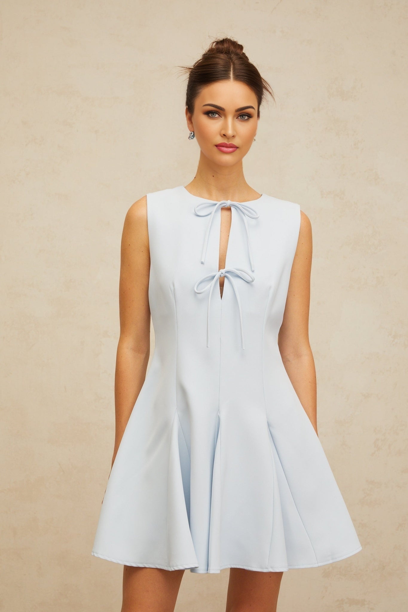 Young woman wearing a blue mini dress with a bowknot detail and godet skirt design