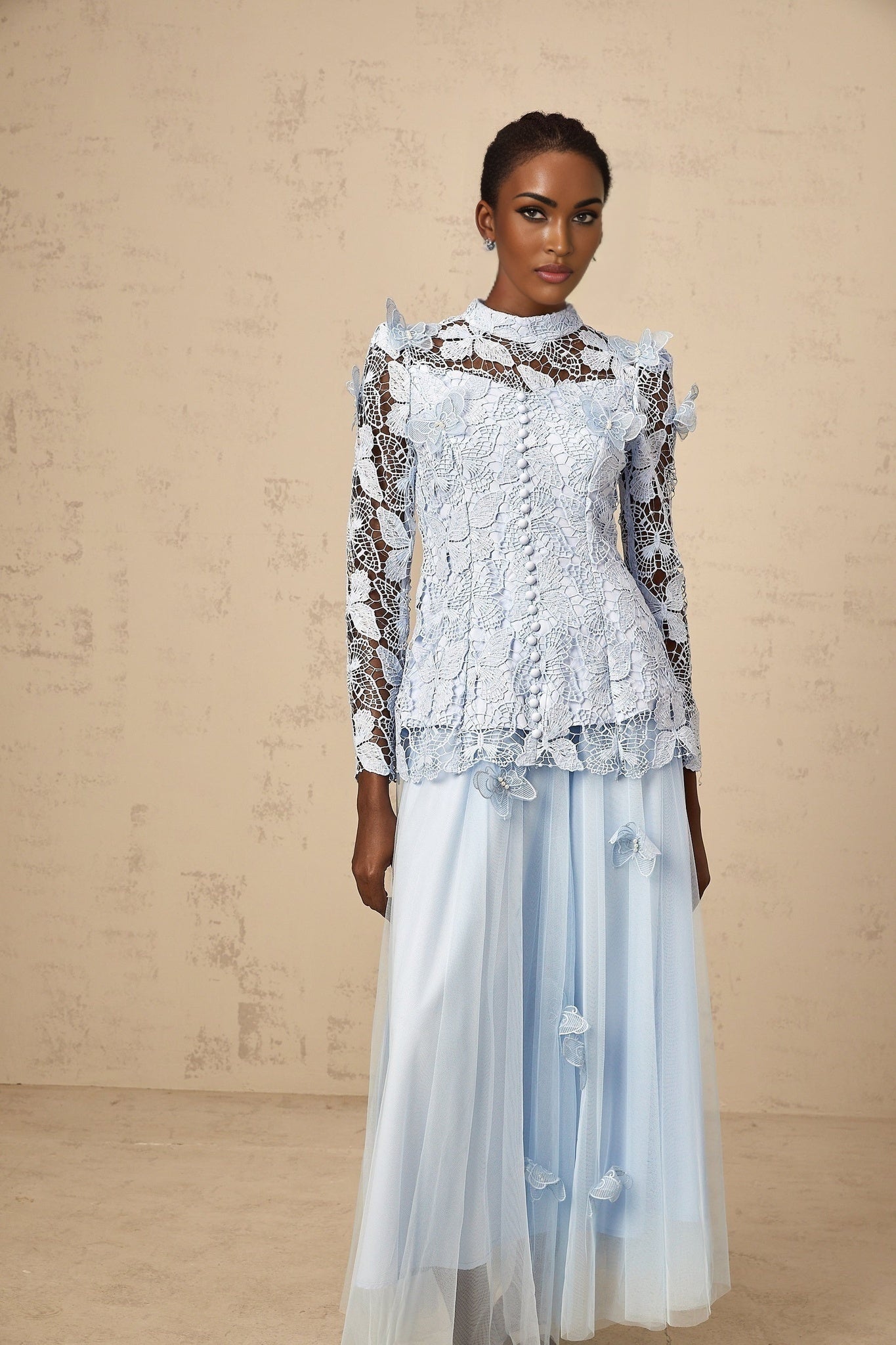 Young woman wearing a blue sequined lace matching set consisting of a sleeveless top and short skirt with shimmering details