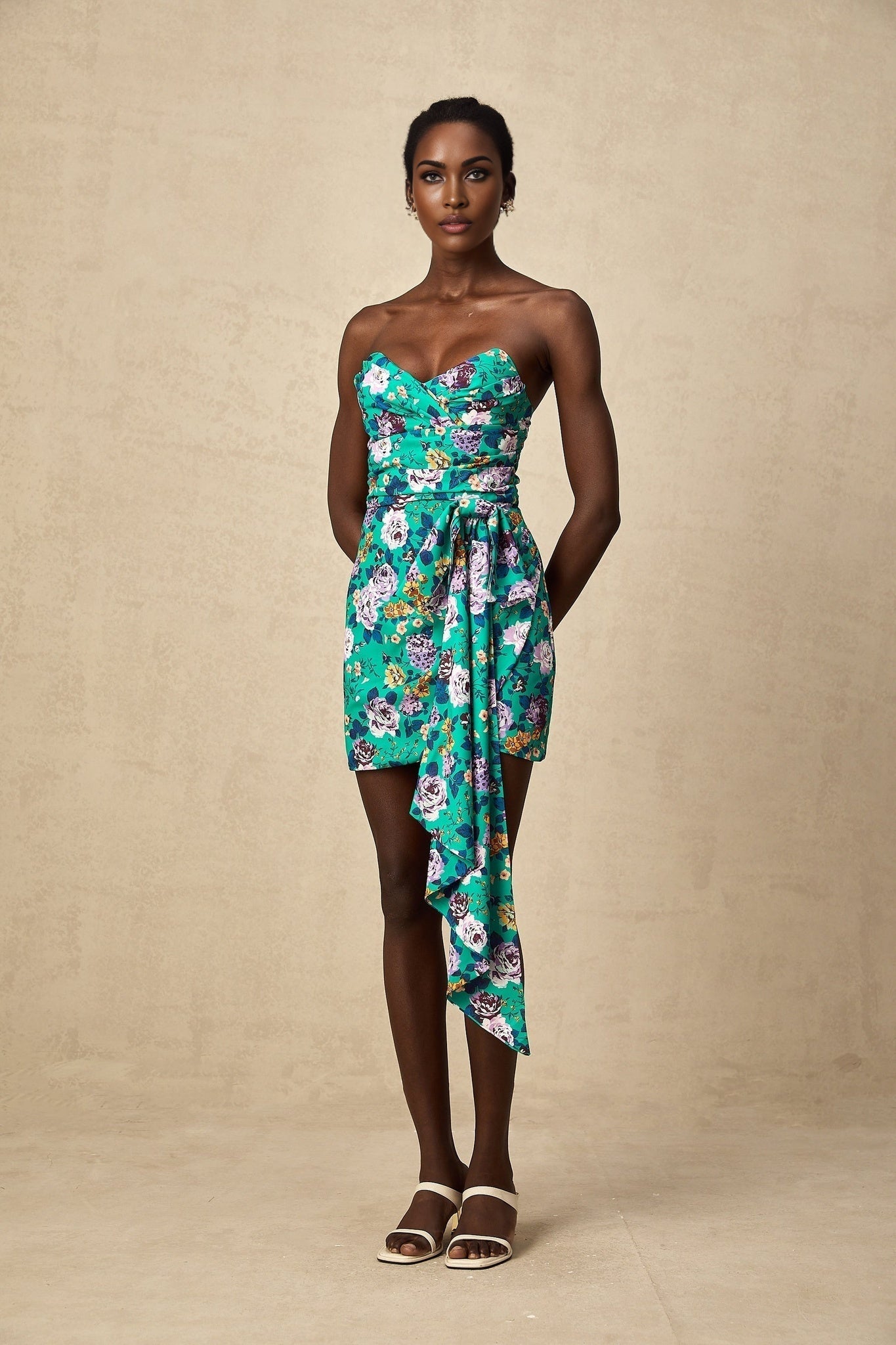 Young woman wearing a green mini dress with floral pattern and ruched detailing