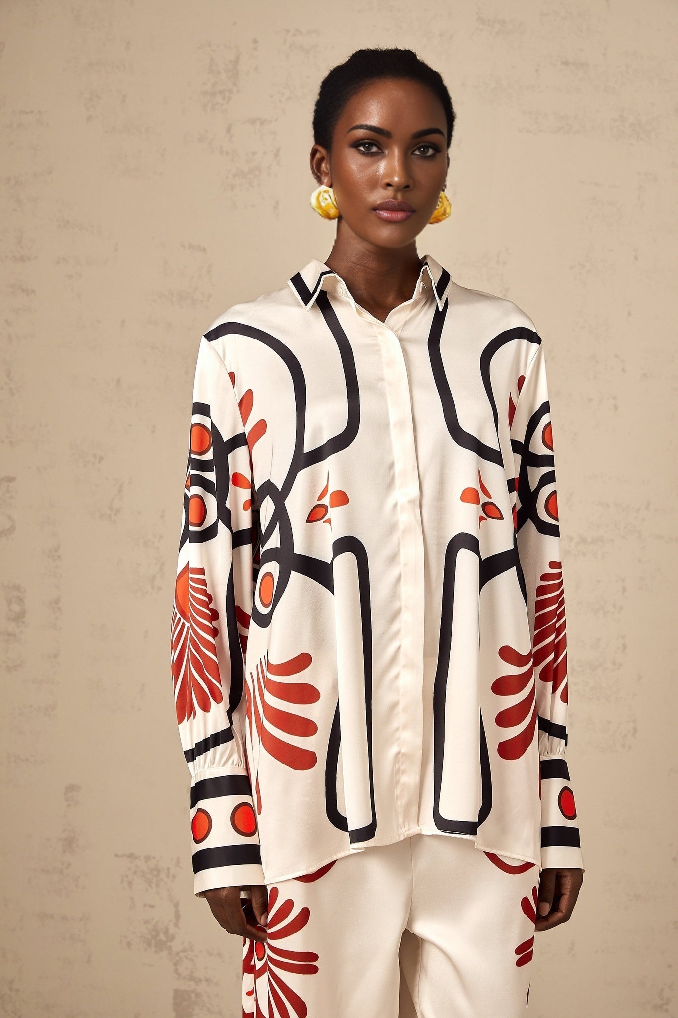 Young woman wearing a matching set consisting of a graphic print shirt and trousers in vibrant colors with floral patterns