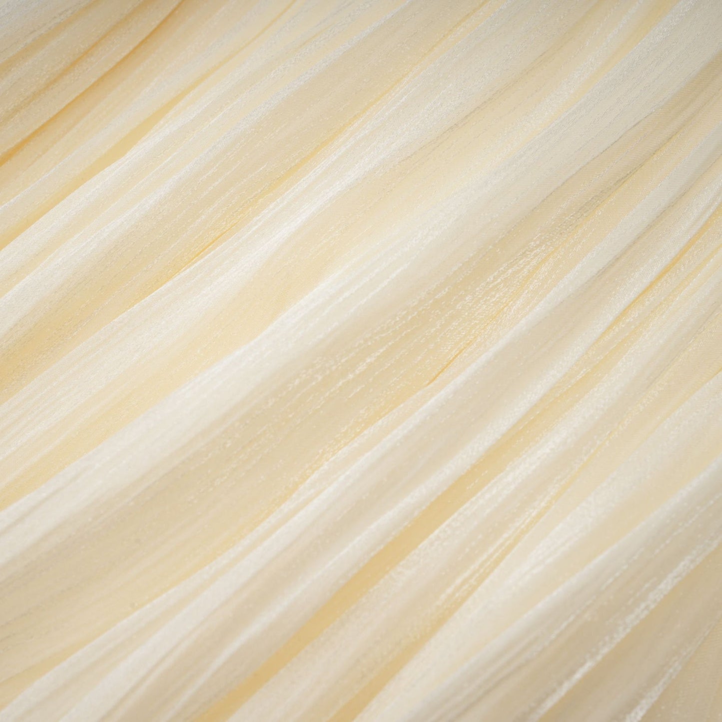 Young woman wearing a short pleated dress with ribbon accents posing against a plain background