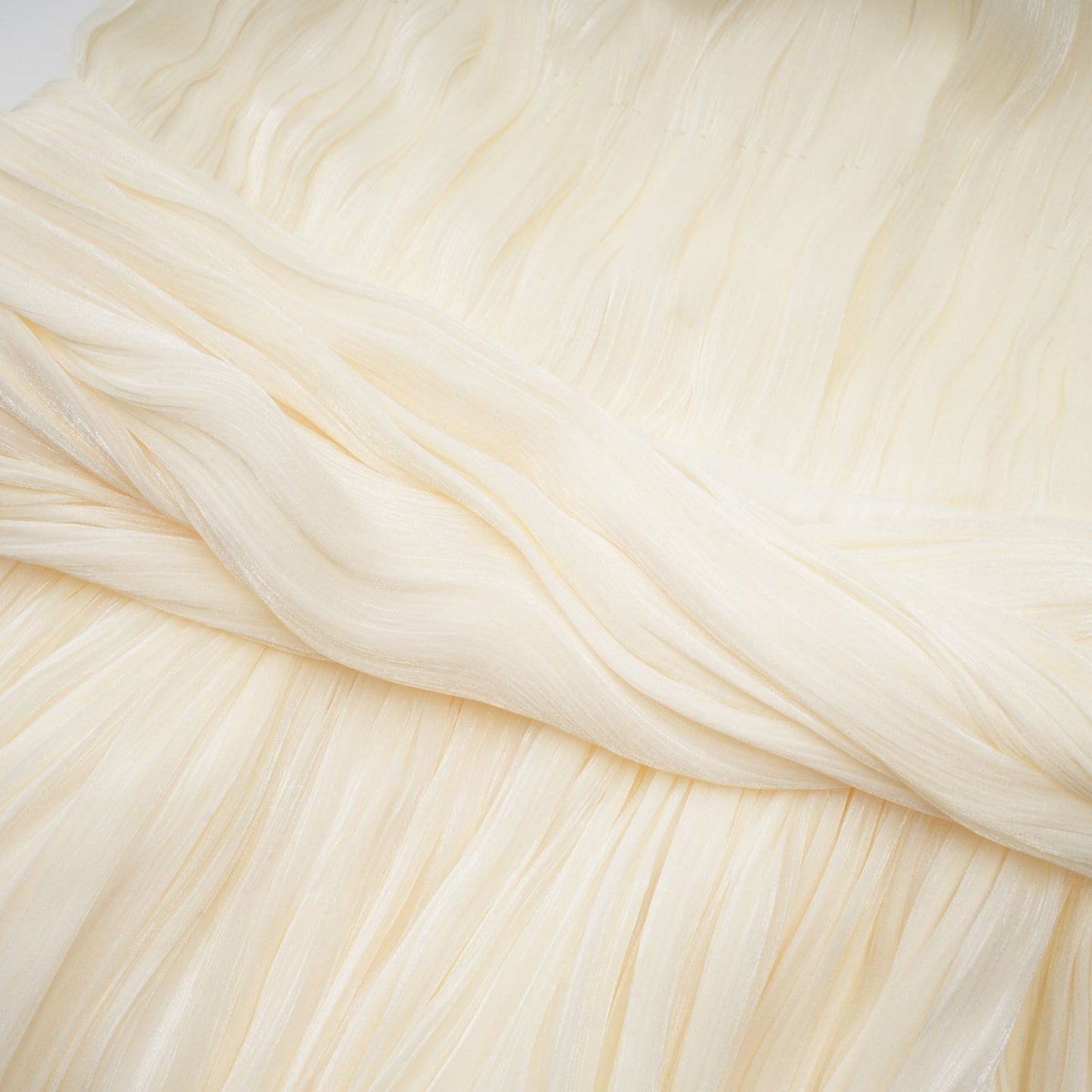 Young woman wearing a short pleated light colored mini dress with ribbon design accents at the waist and neckline