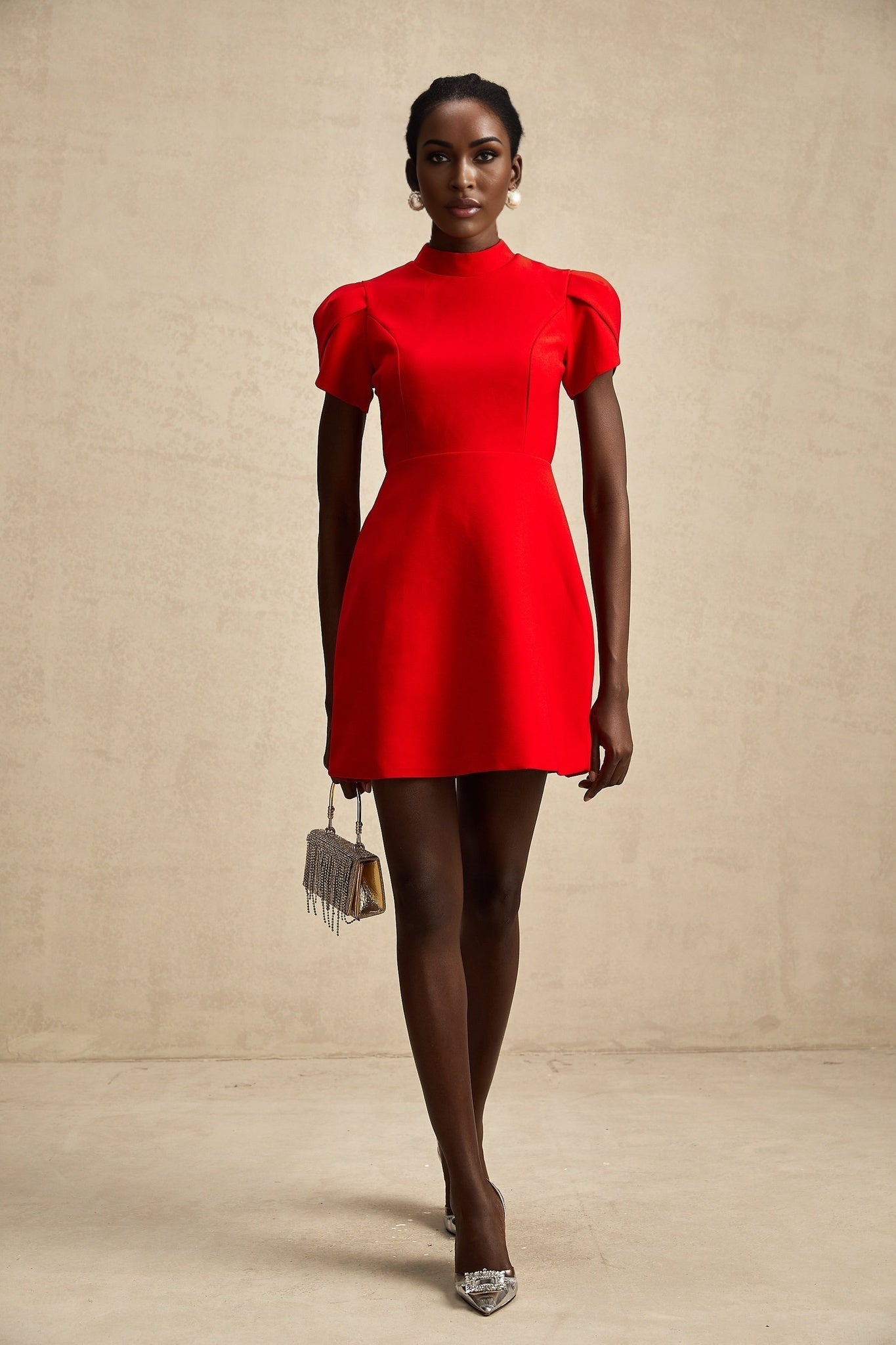 Young woman wearing a short red dress with petal sleeves and a cutout design featuring a bow detail